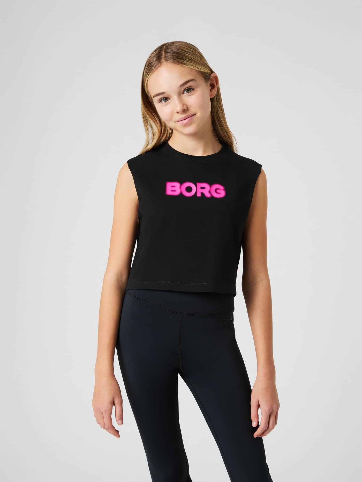 Vista frontal de modelo kids con Borg Cropped Tank Top en Black Beauty (Negro) y logo rosa para entrenamiento. - Image 1