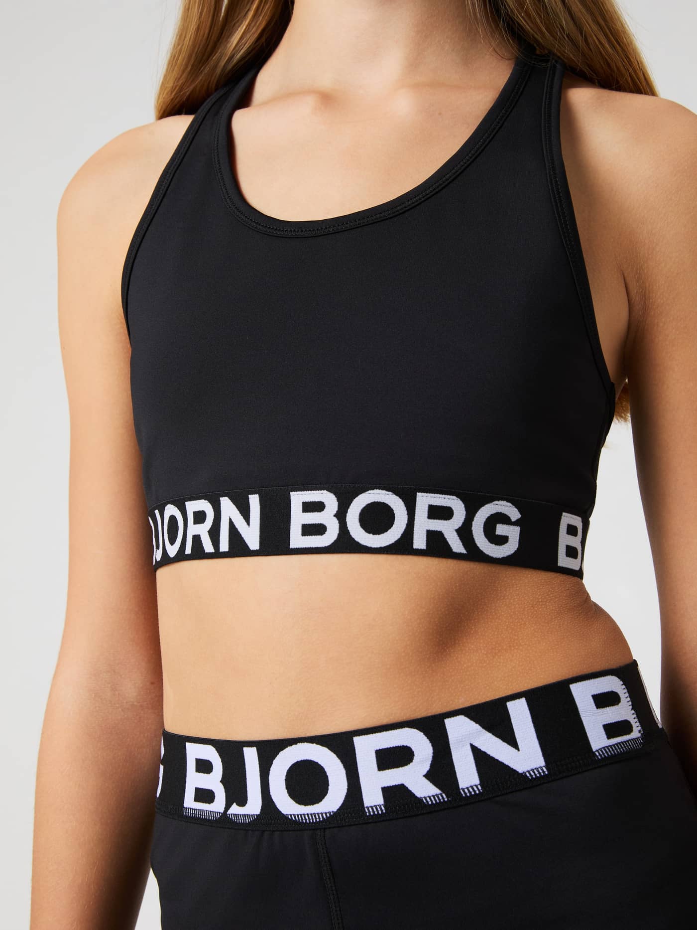 Front torso view of the black Borg Sports Top for kids' training, featuring a white logo on the elastic band. - Image 4