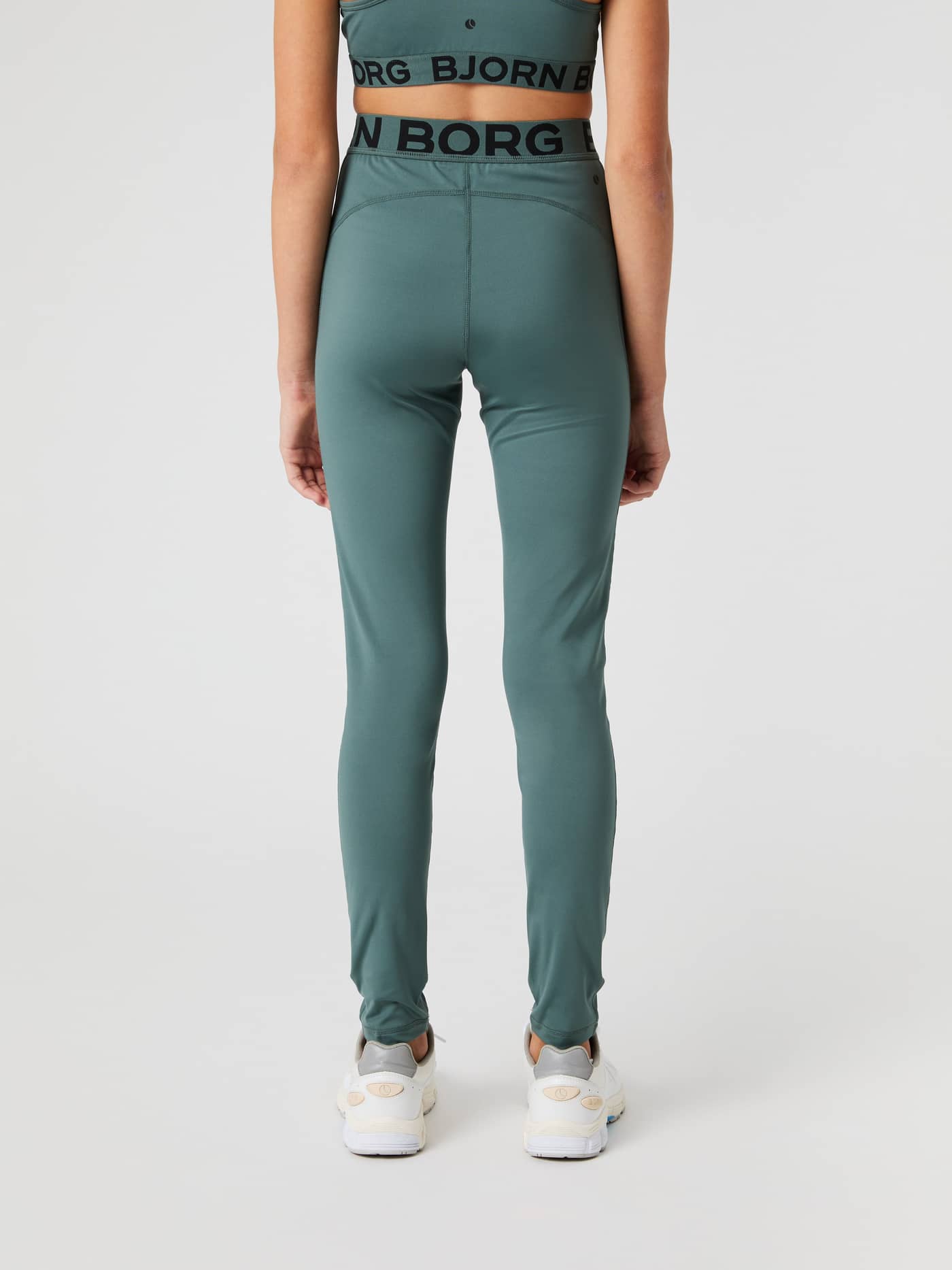 Back view of a kid wearing Balsam Green (Green) Borg Leggings featuring a black logo elastic waistband. - Image 2