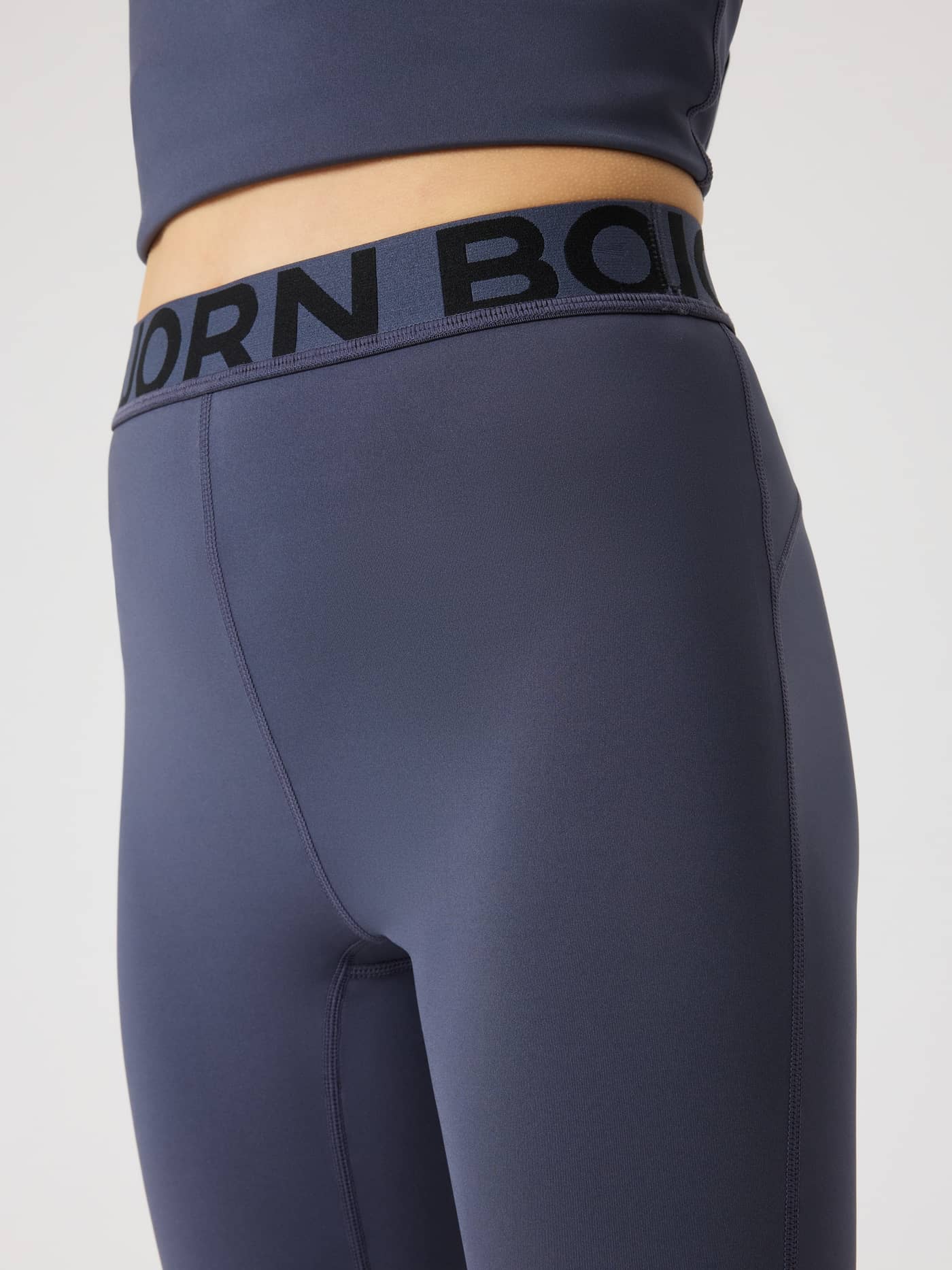 Close-up of the kids' Borg Leggings in Odyssey Gray (Navy) with a black logo on the elastic waistband for training. - Image 4