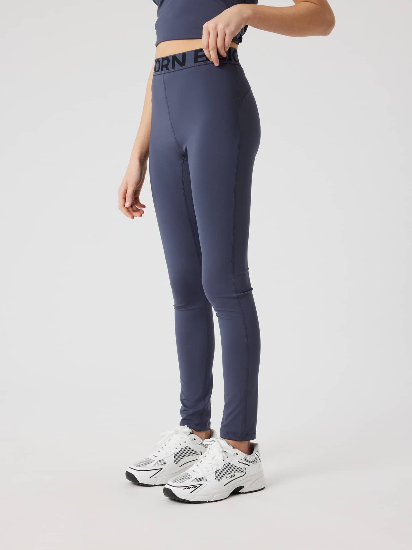 Side view of kids wearing training Björn Borg Leggings in Odyssey Gray (navy) with a black logo on the waistband. - Image 2