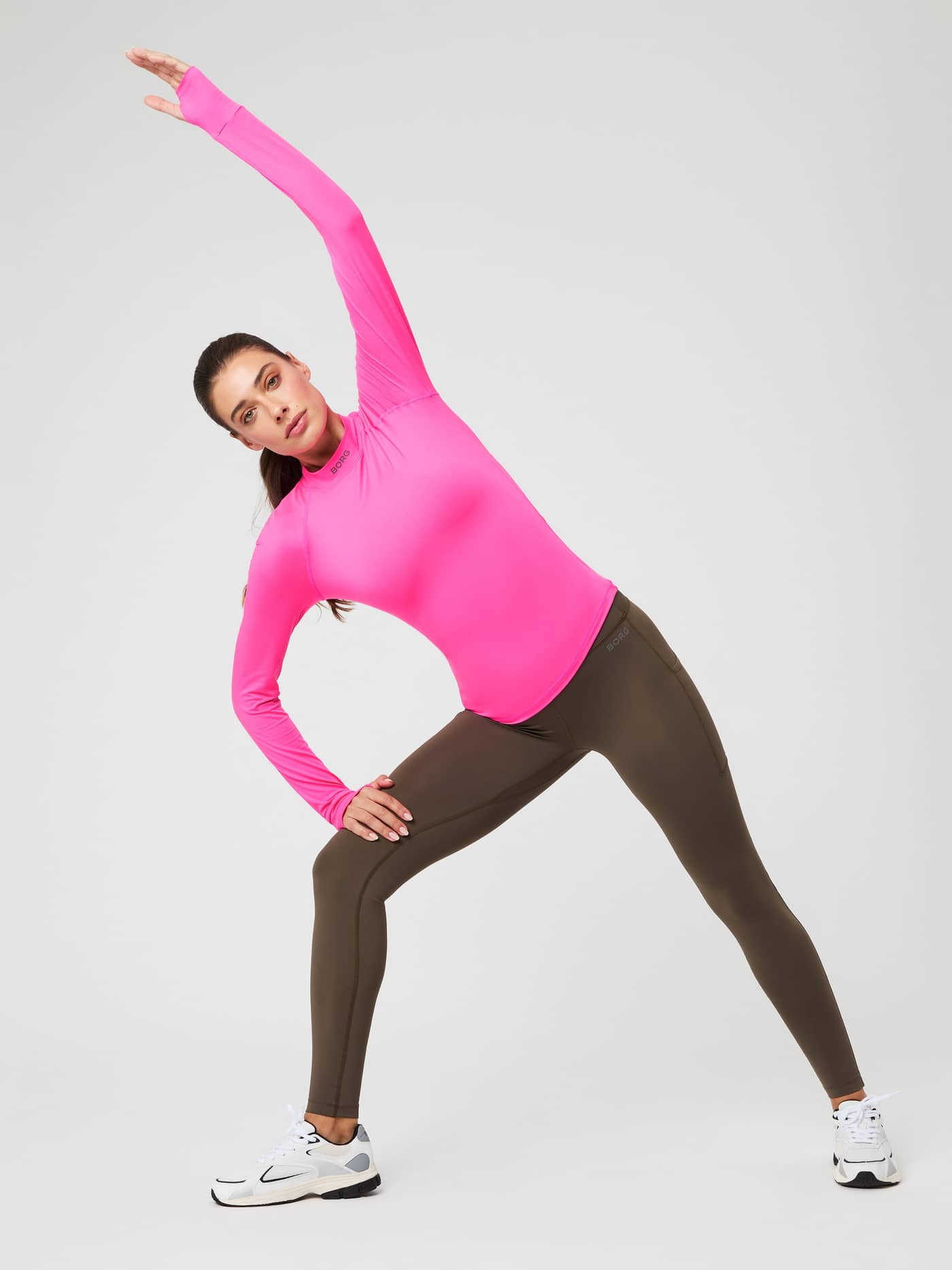 Full-body view of a woman stretching in the Pink Glo (Pink) Borg Performance Brushed Mockneck, a slim-fit running top. - Image 2