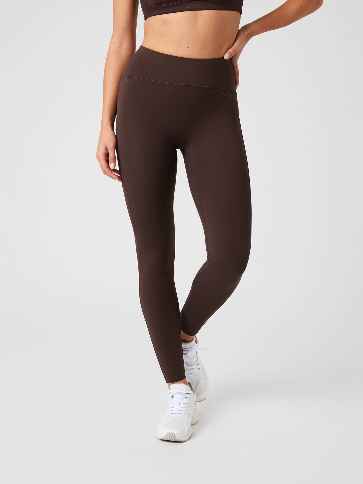 Front view of a woman wearing the brown, high-waisted Borg Reform Tights. - Image 1