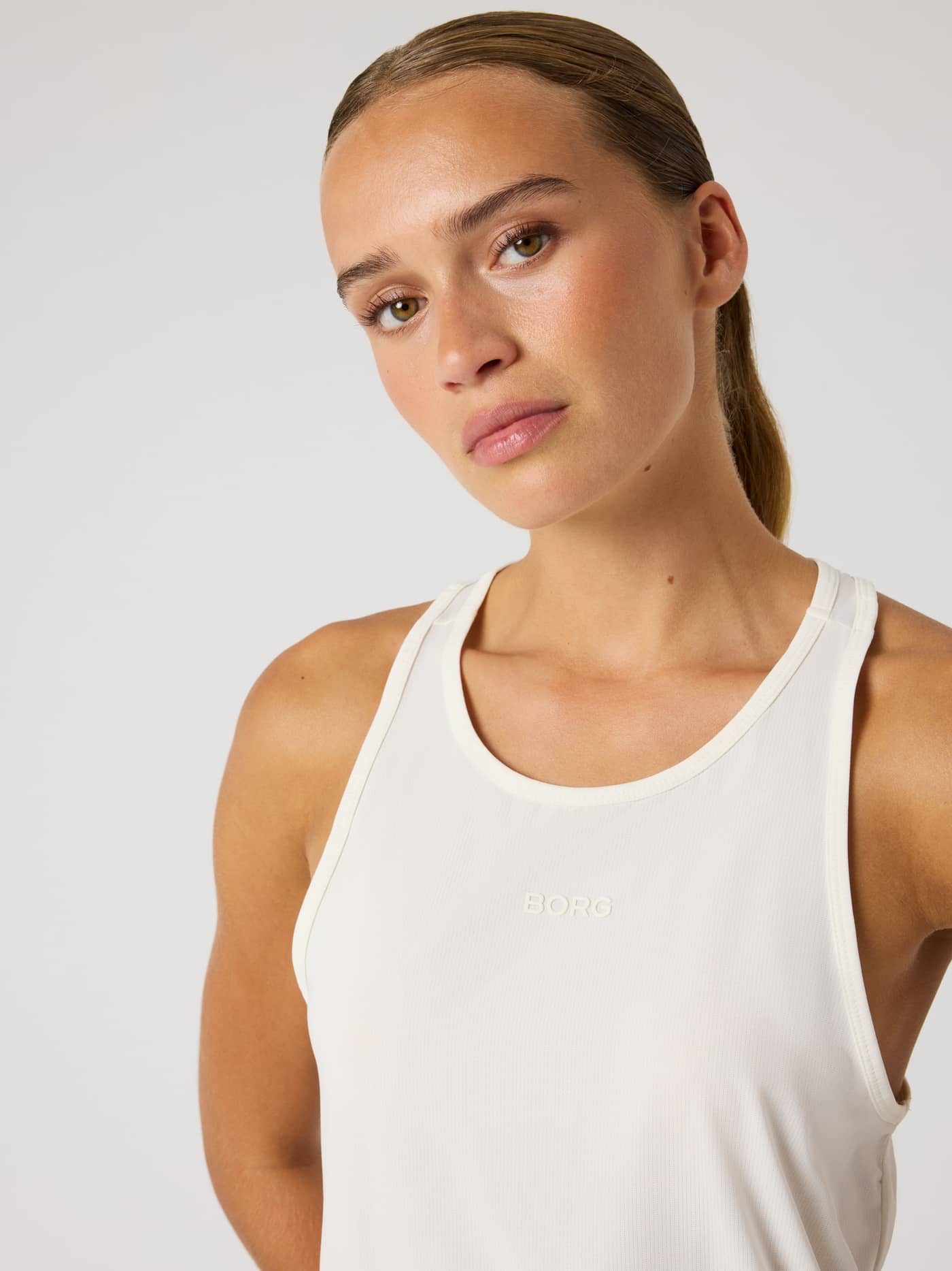 Front close-up of a model wearing the training Borg Sports Tank Top in Tofu (White) with a tonal logo. - Image 5