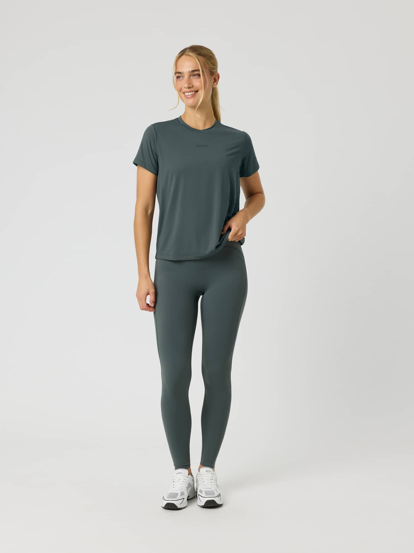 Full-body front view of a woman in the Borg Sports T-Shirt in Urban Chic (Green) with a tonal logo for training. - Image 3