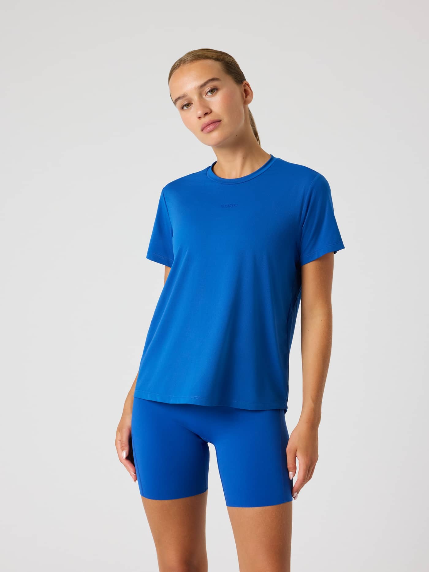 Vorderansicht einer Frau im Monaco Blue (Blau) Borg Sports T-Shirt, atmungsaktives Trainings-Top mit idealer Passform. - Image 1