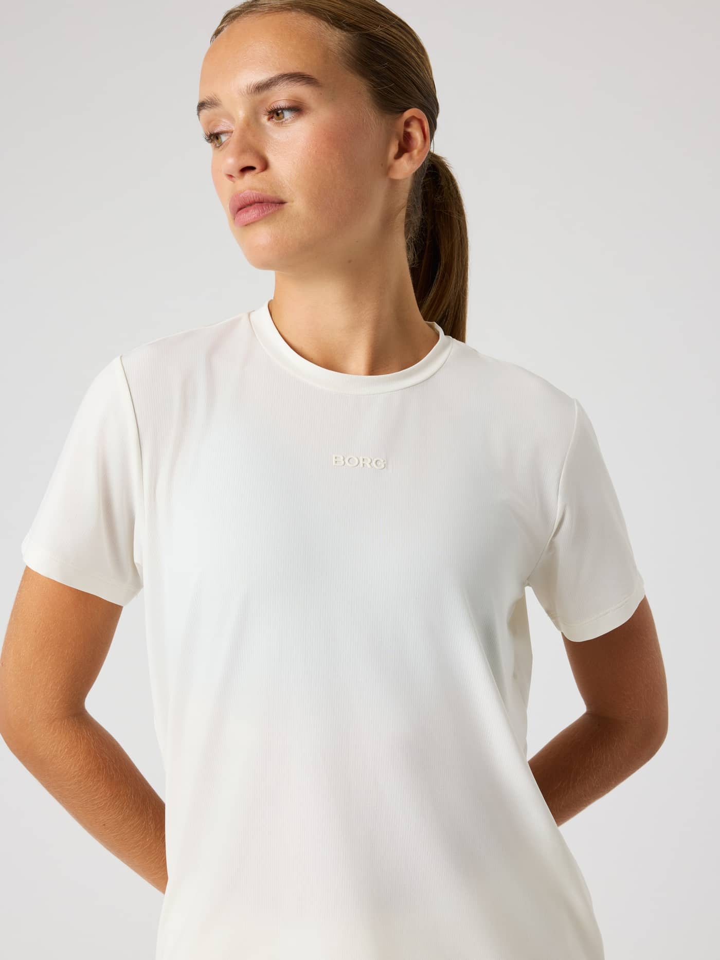 Front view of a woman in the Borg Sports T-Shirt in Tofu (White), a breathable training tee with a tonal logo and sleek fit. - Image 5