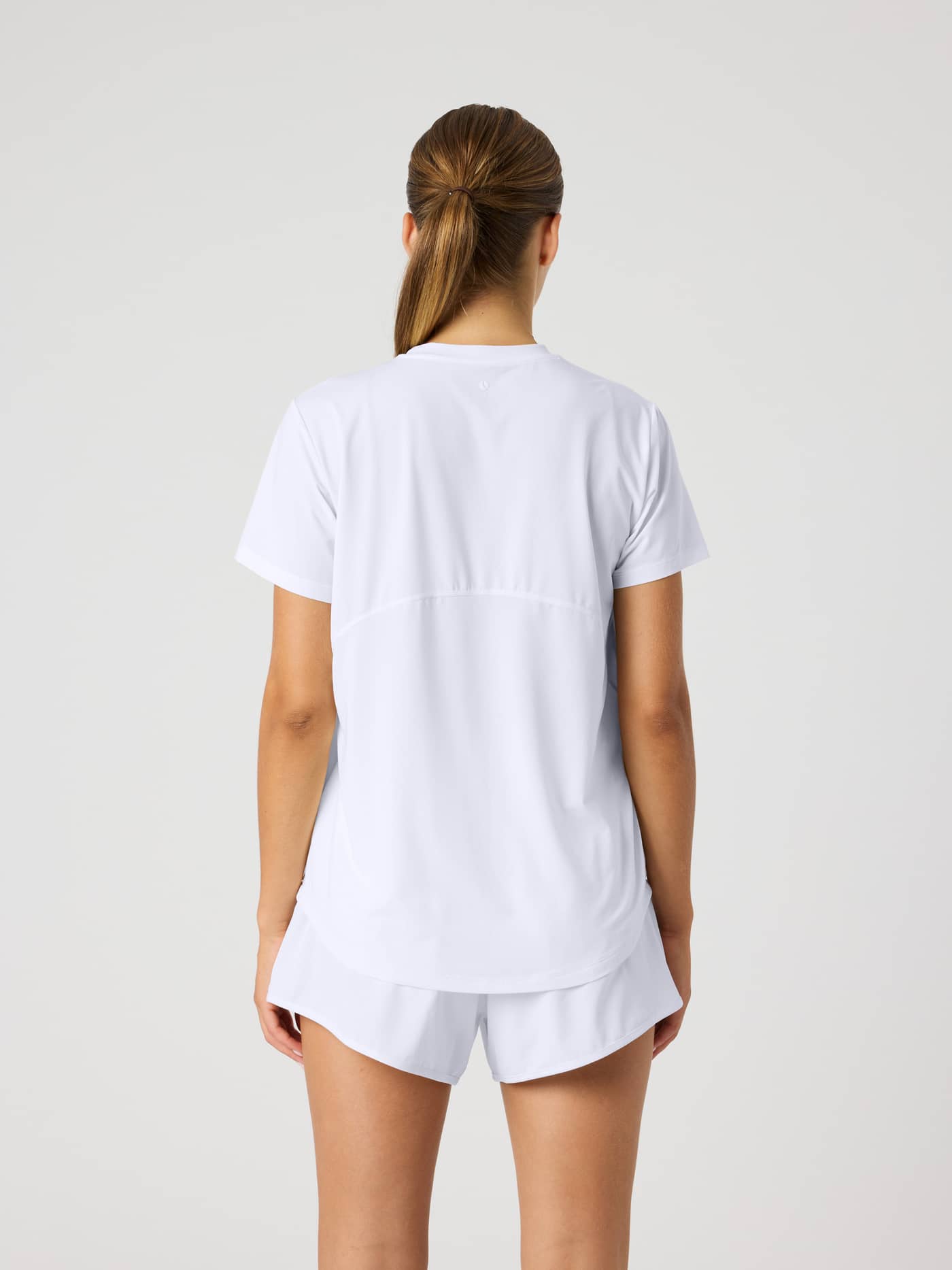 Back view of a woman wearing the training Borg Sports T-Shirt in Brilliant White (White) with a detailed back seam. - Image 2