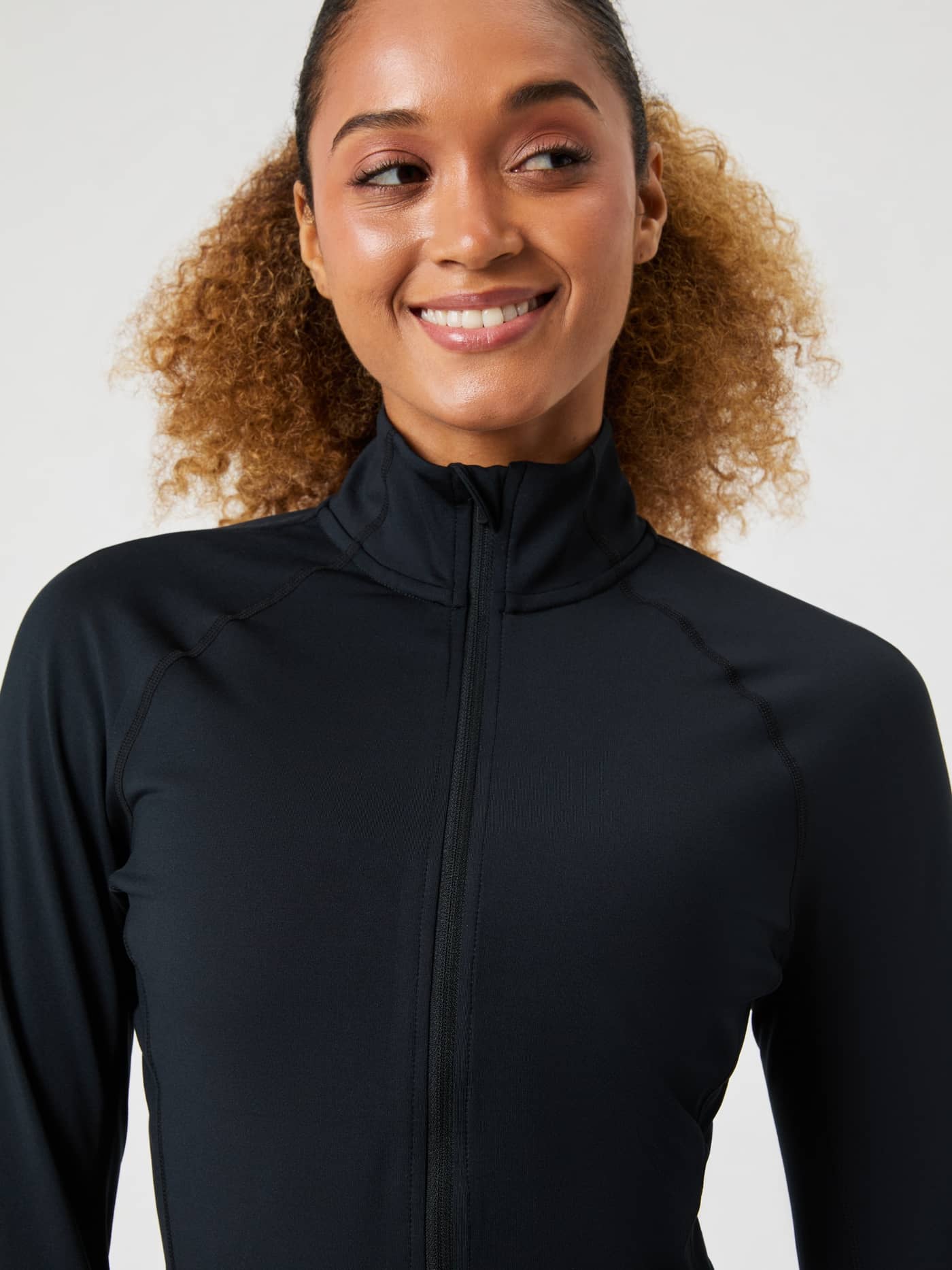 Close-up of a woman smiling, wearing the black Borg Full Zip Midlayer, showing the high collar and zip detail. - Image 2