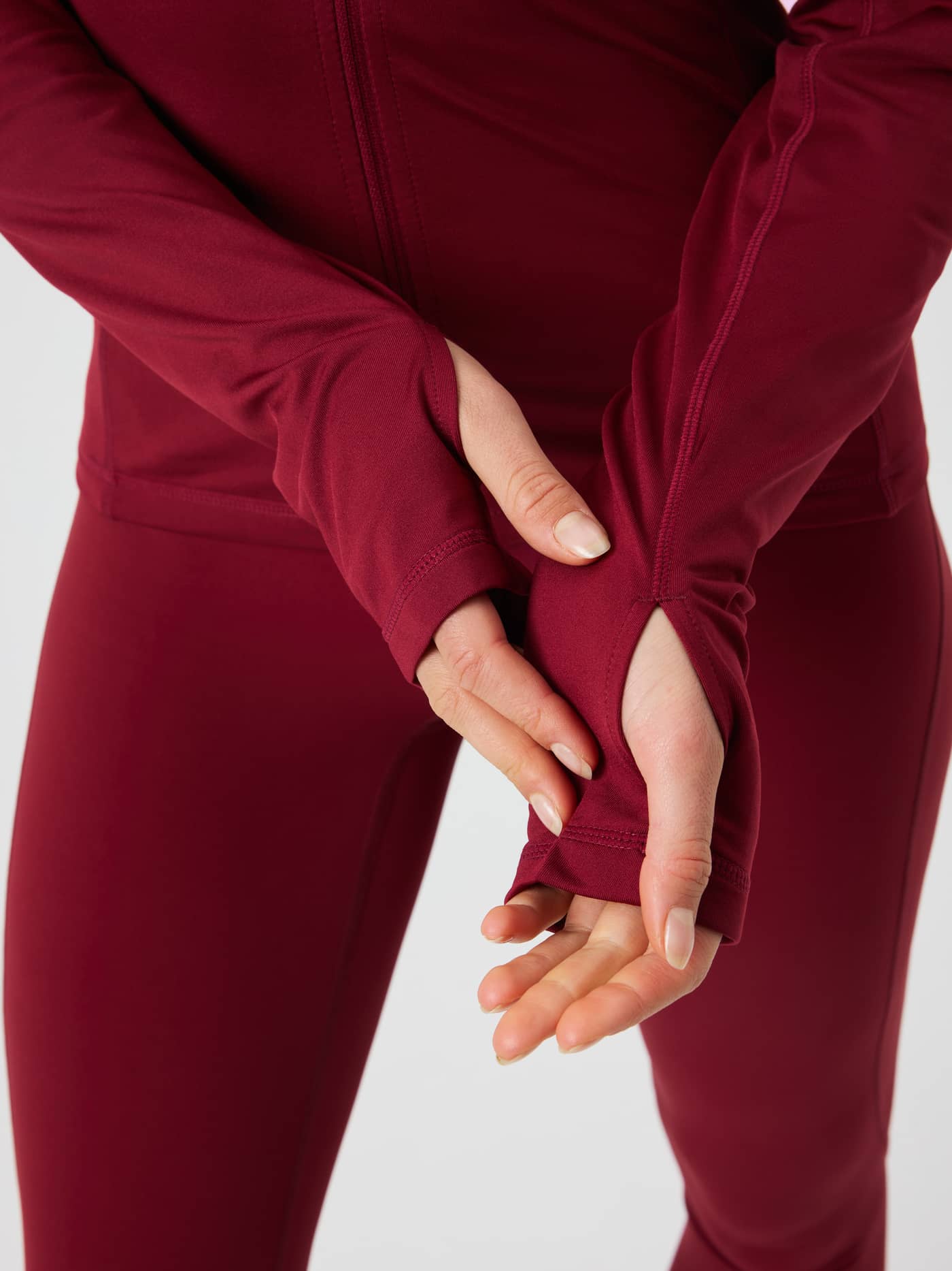 Close-up van de Borg Full Zip Midlayer in Cabernet (Rood) met focus op de duimgaten in de lange mouwen voor training. - Image 4