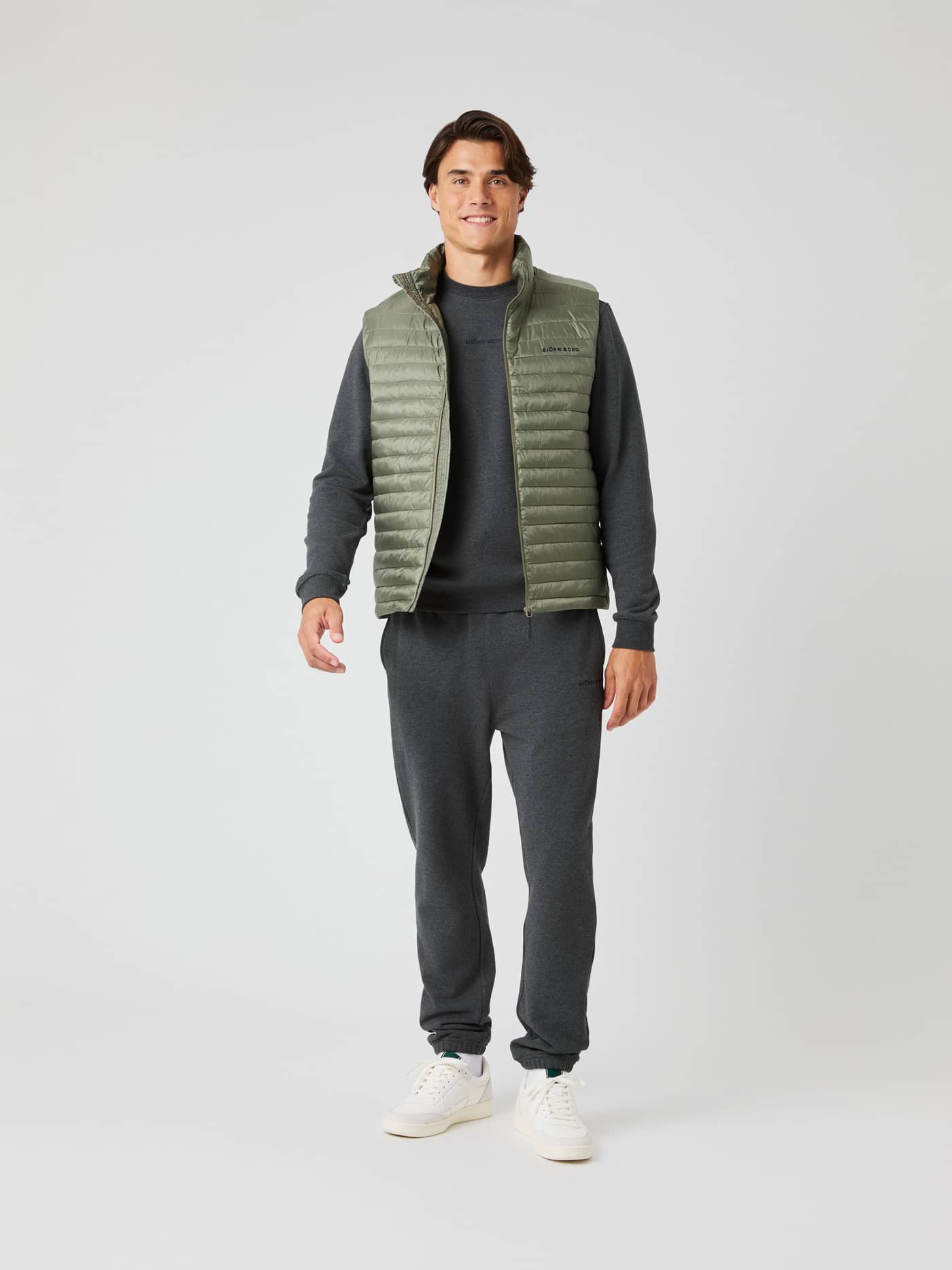Full-body front view of a man wearing the Borg Light Padded Vest in Dusty Olive (Green) over a grey sweatshirt. - Image 4