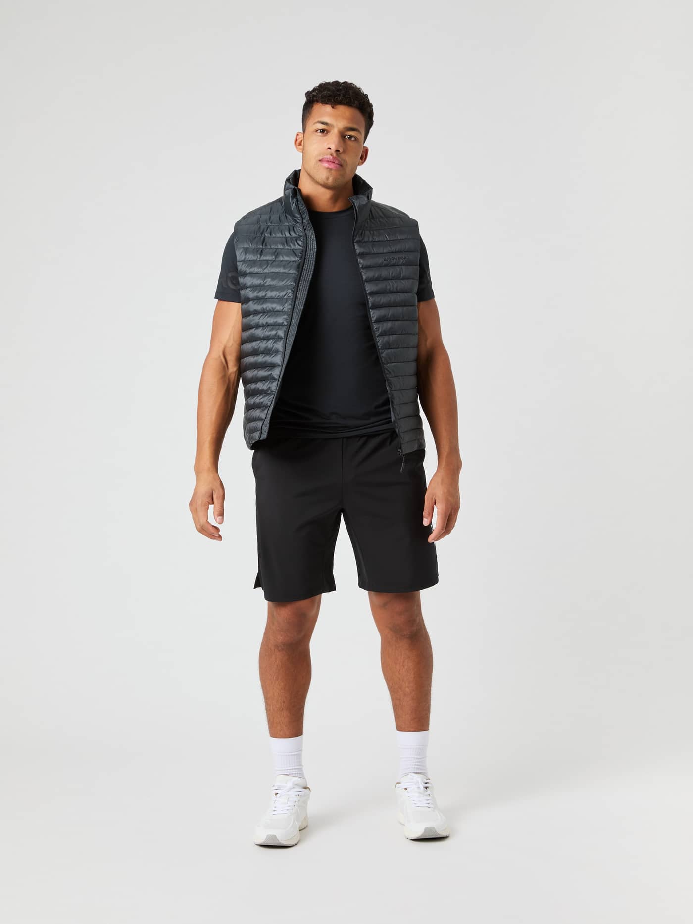 Full-body front view of a man wearing the Borg Light Padded Vest in Black Beauty (Black) for a functional outerwear style. - Image 3
