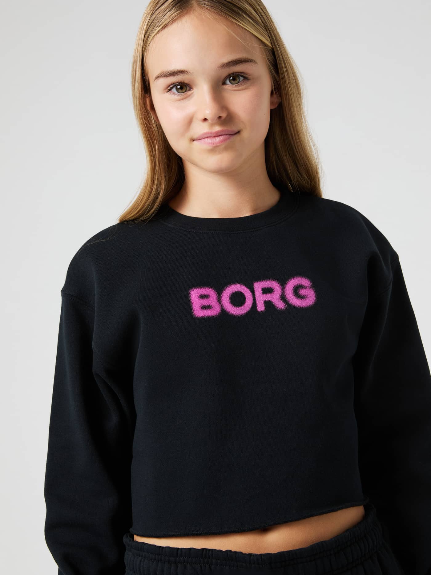 Primer plano de niña con Borg Oversized Cropped Sweatshirt en Black Beauty (Negro) y logo rosa para kids. - Image 4