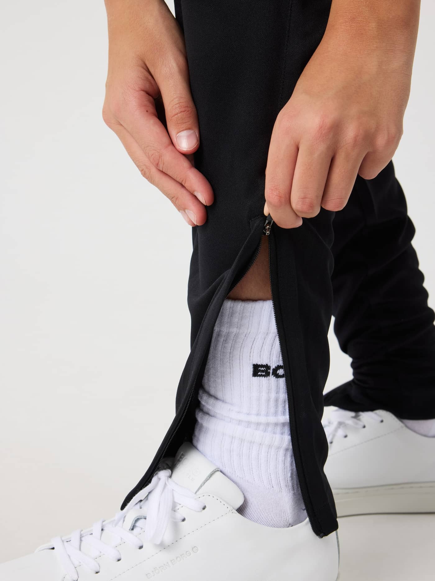 Detailed close-up of the ankle zipper on kids' Borg Active Pants in Black Beauty (Black) for training performance. - Image 4