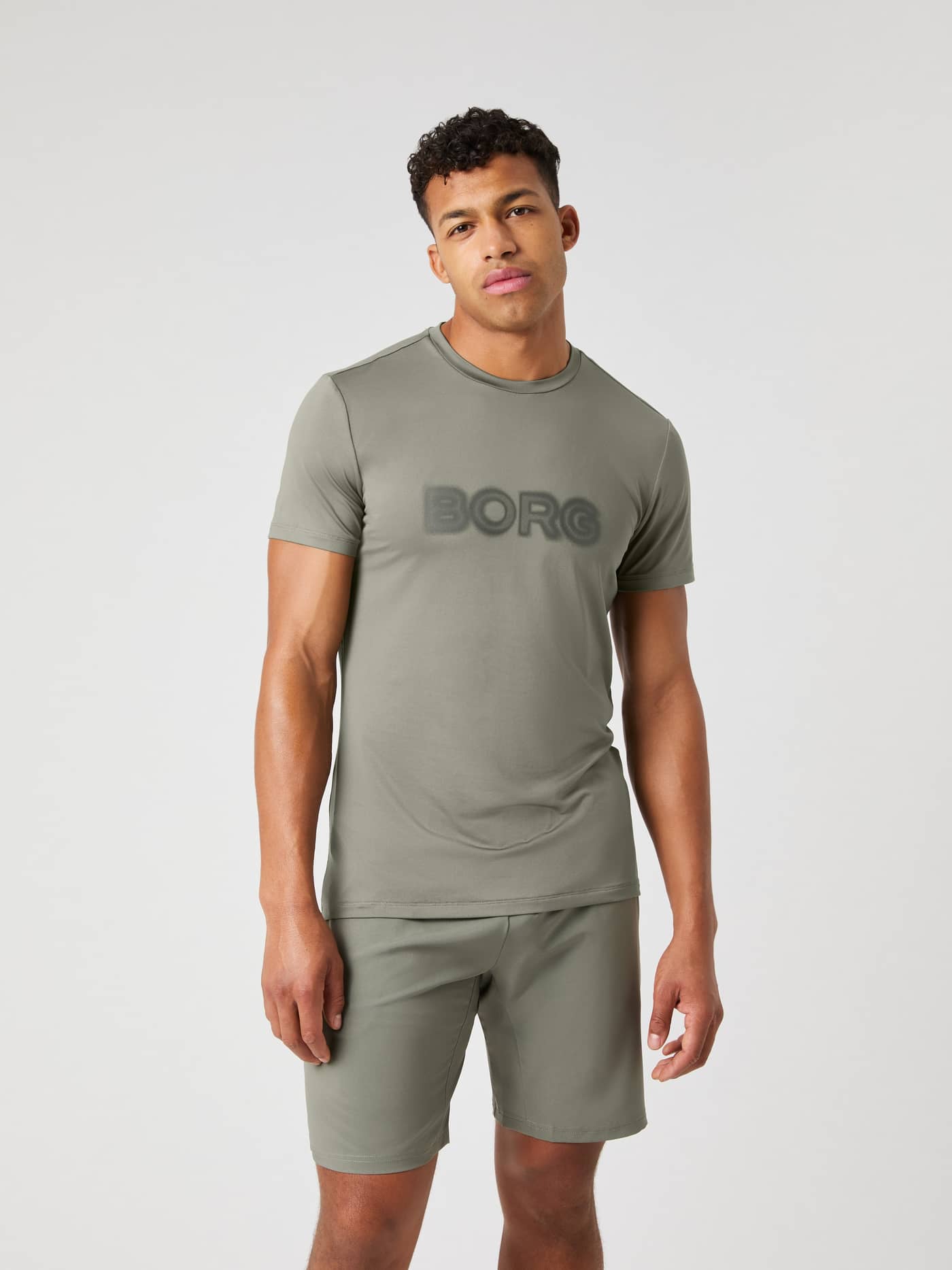 Vorderansicht eines Models im Borg Graphic T-Shirt in Dusty Olive (Grün) für Training mit Performance und Style. - Image 2