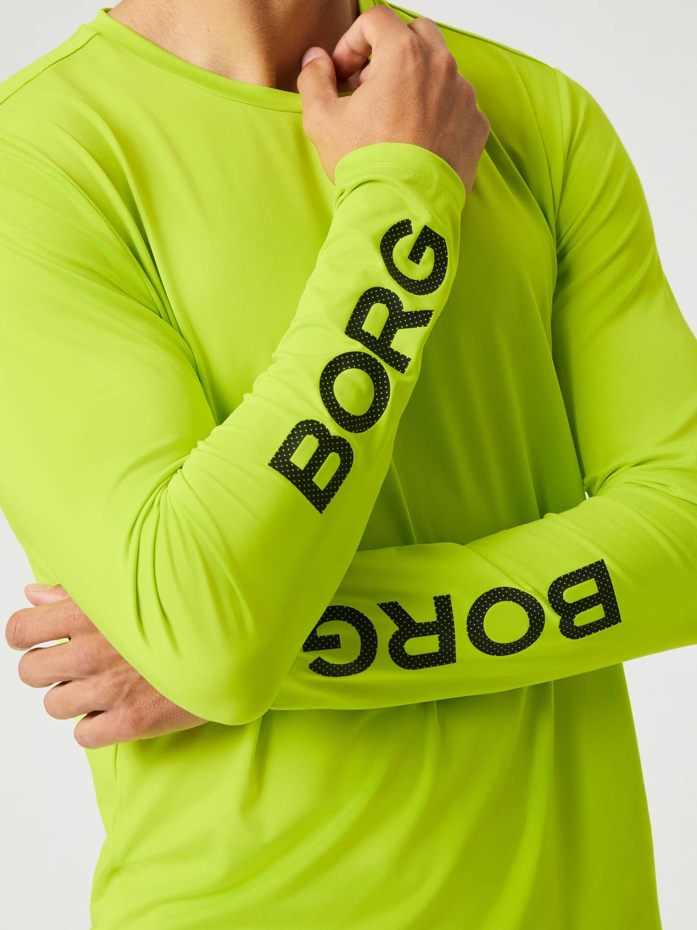 Modell i Borg Long Sleeve T-Shirt i Acid Lime (Grön) med korsade armar som visar svarta BORG-logotyper för träning. - Image 4