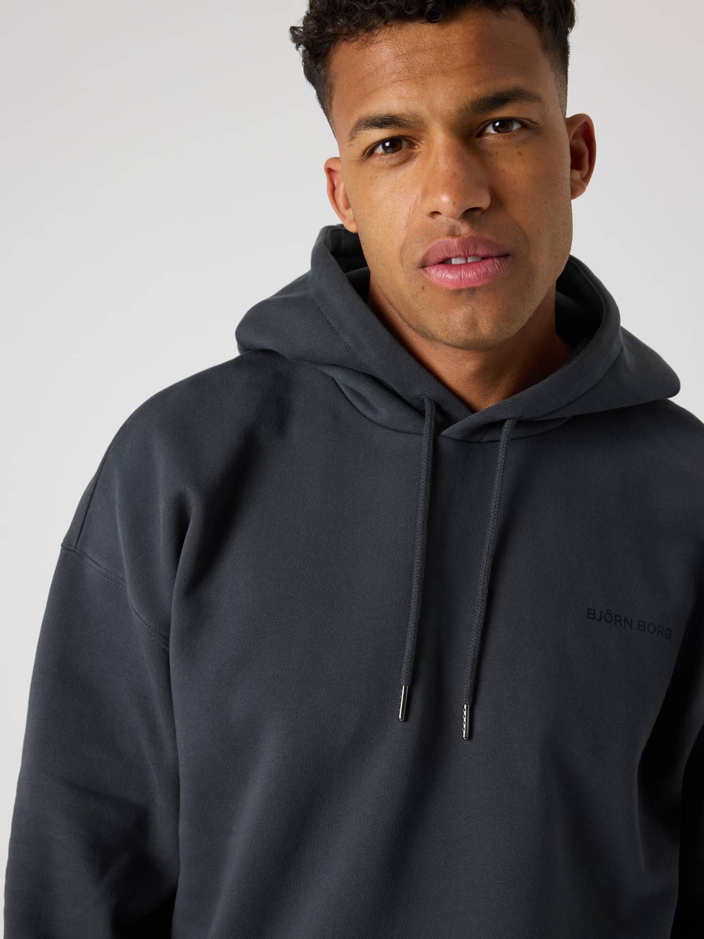 Borg Oversized Hoodie i Asphalt (Grå) set forfra i nærbillede med en blød pasform og stilfuldt brystlogo. - Image 4