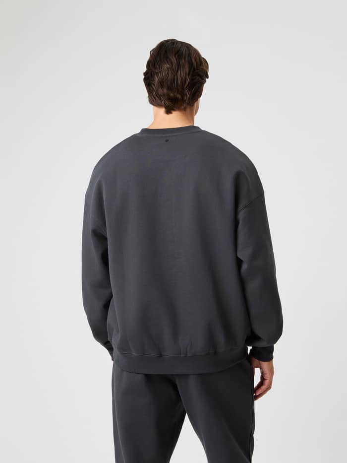 Achteraanzicht van een man in het Borg Oversized Sweatshirt in Asphalt (Grijs) van zachte katoenmix met zwart neklogo. - Image 3