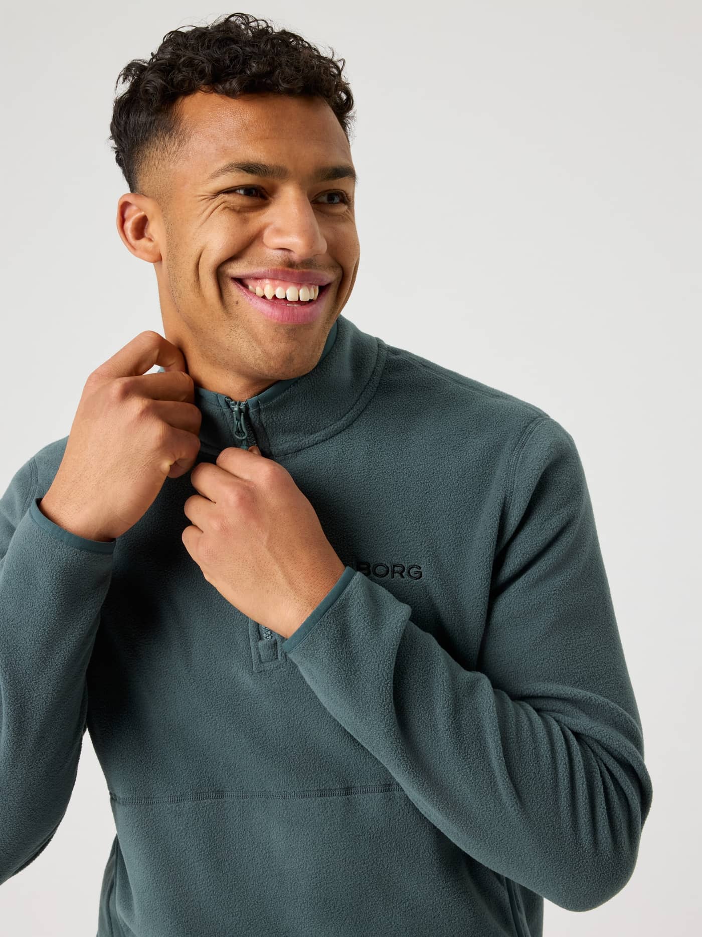 Close-up front view of a man wearing the soft Björn Borg Half Zip Fleece in Urban Chic (Green) with a black logo. - Image 4