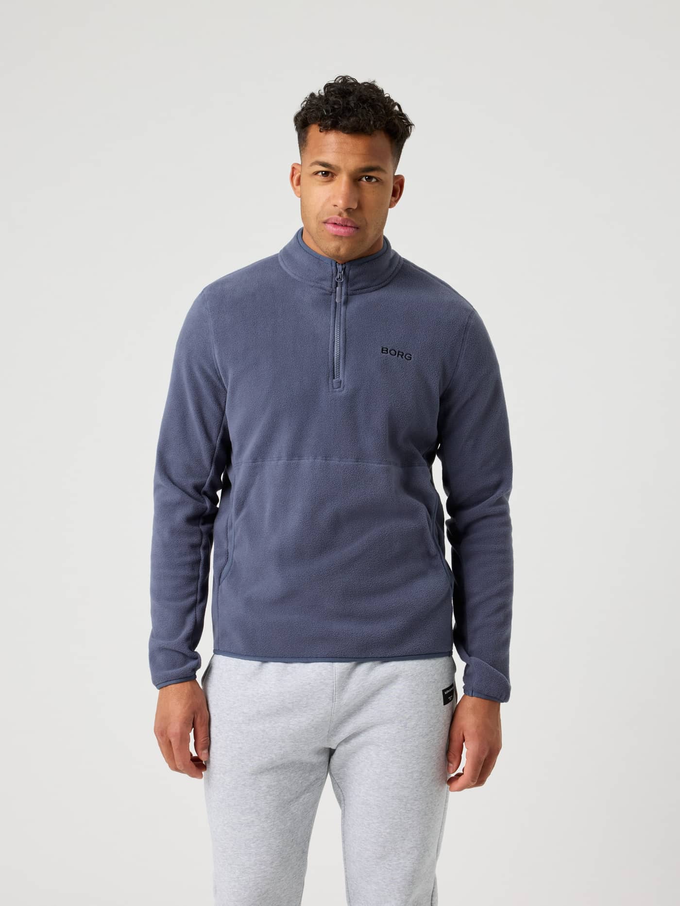 Front view of a man wearing the functional Borg Half Zip Fleece in Odyssey Gray (Blue) with a black logo on the chest. - Image 3
