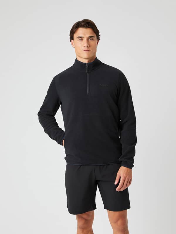 Borg Half Zip Fleece i Black Beauty (Svart) sedd framifrån på en modell med handen i fickan för en funktionell stil.