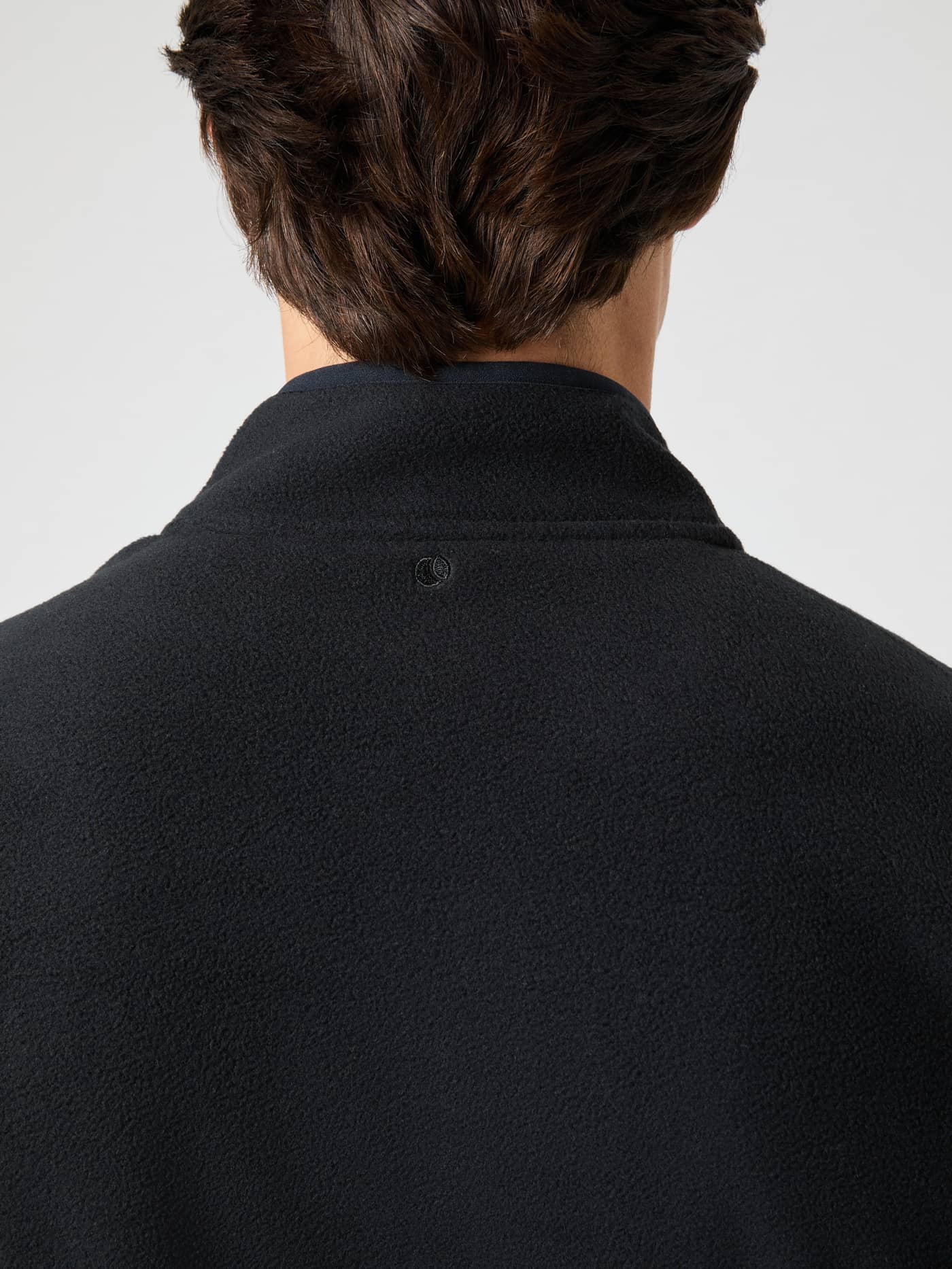 Back view of a man wearing the Borg Full Zip Fleece in Black Beauty (Black), featuring soft fleece and a black neck logo. - Image 5