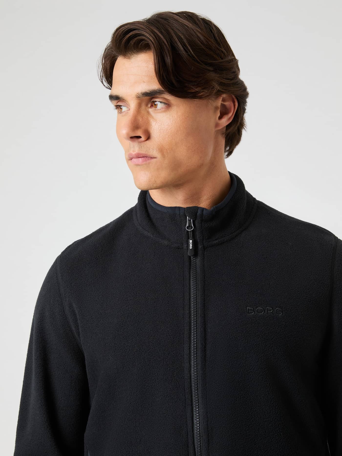 Close-up of a man wearing the Borg Full Zip Fleece in Black Beauty (Black) featuring warm fleece and a black logo. - Image 4