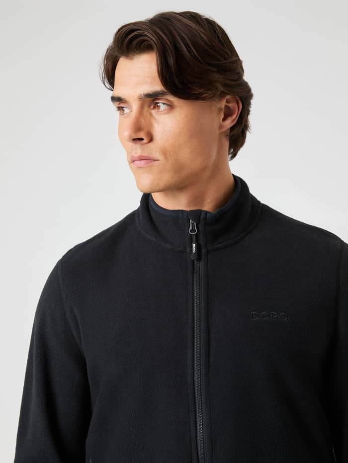 Close-up van een man in de Borg Full Zip Fleece in Black Beauty (Zwart) van warm fleece met een zwart logo. - Image 4