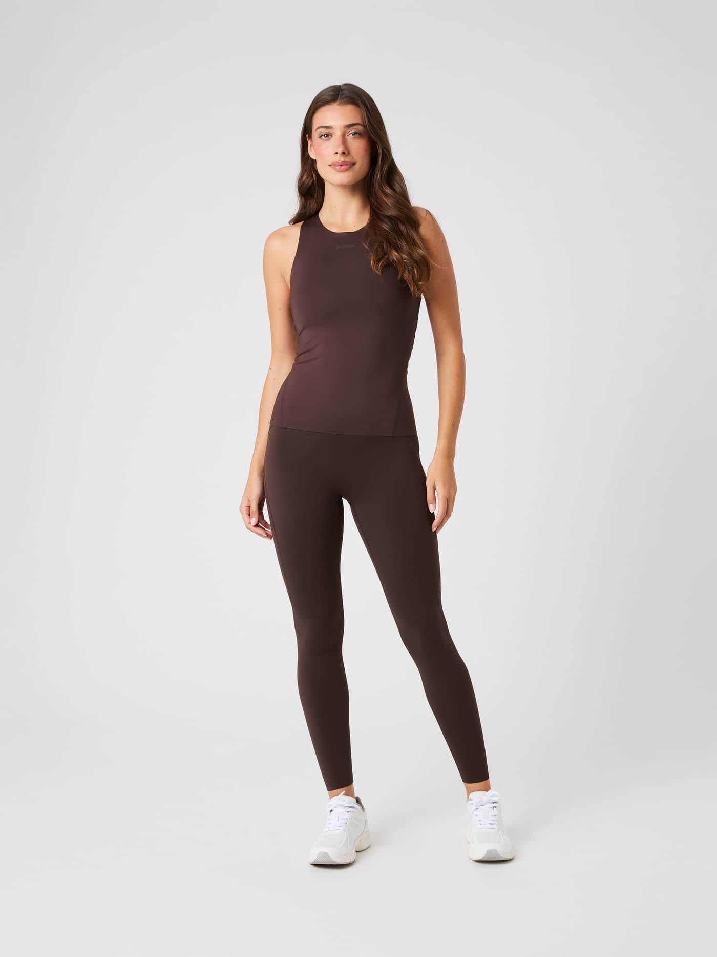Full-body front view of a woman wearing the Molé (Brown) Borg 2 In 1 Tank Top for training, paired with matching leggings. - Image 3