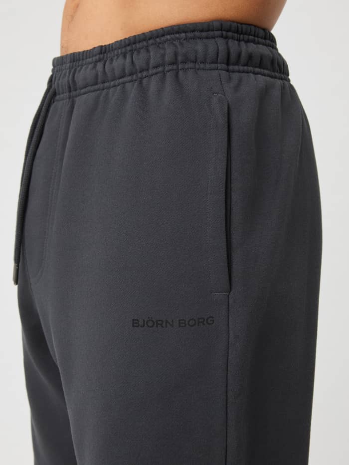 Gedetailleerd zijaanzicht van de Borg Oversized Sweatpants in Asphalt (Grijs) met elastische tailleband en zwart logo. - Image 4