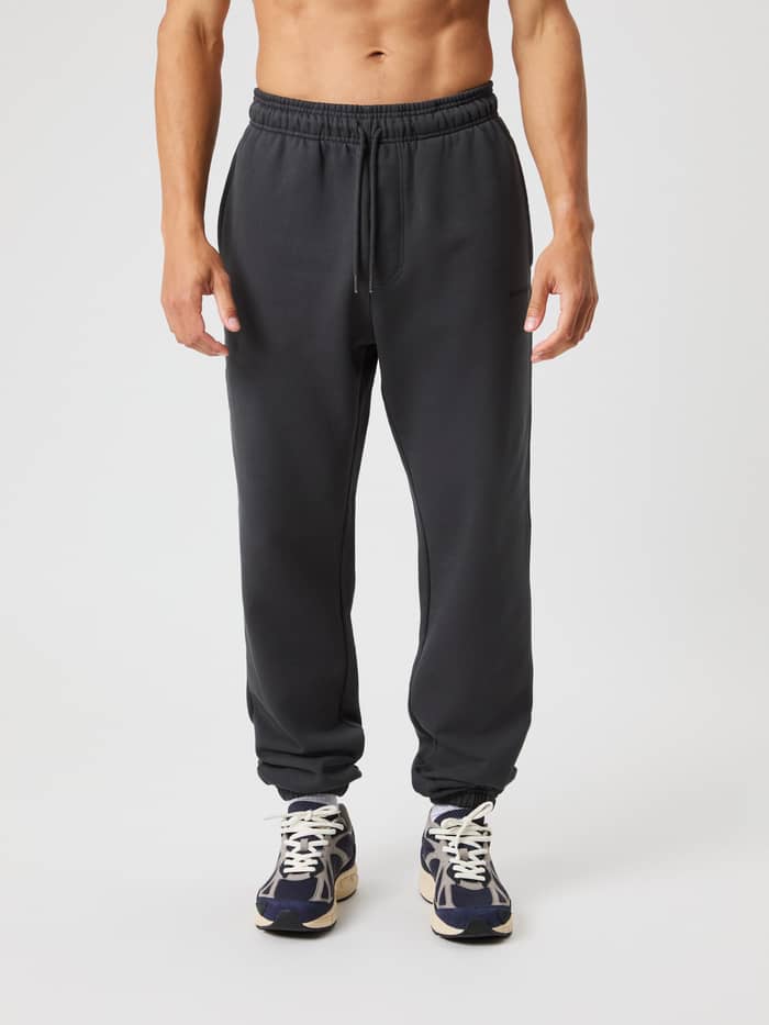 Front view of a man wearing the Borg Oversized Sweatpants in Asphalt (Grey) with a soft cotton leisure fit and black logo.