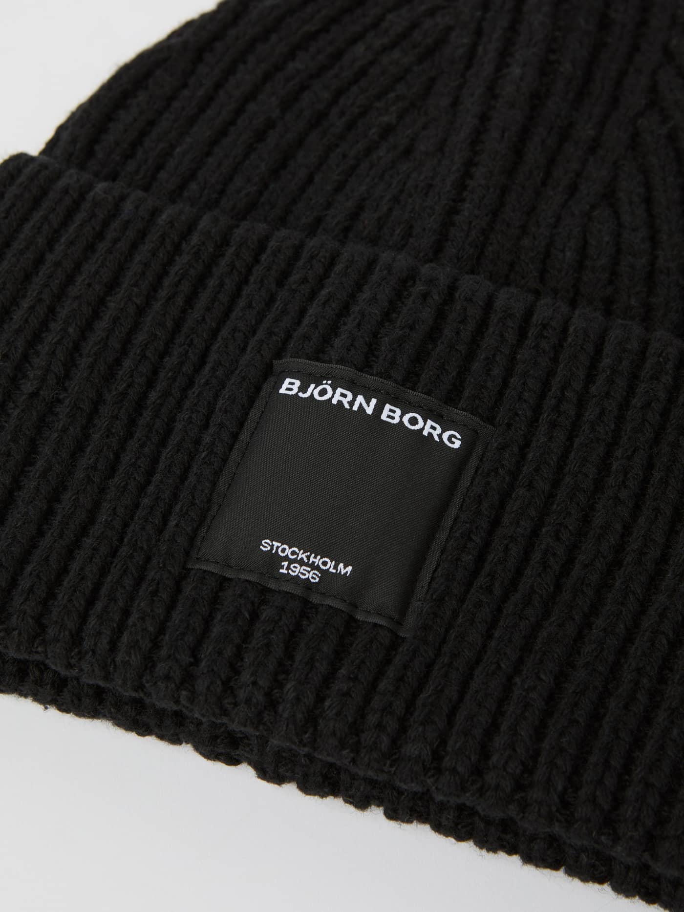 Detailed close-up of the ribbed Centre Knit Beanie in Black Beauty (Black), highlighting the signature front logo label. - Image 2