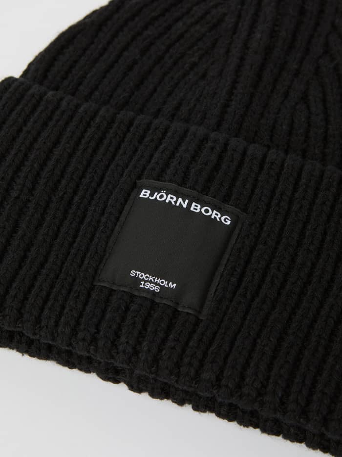 Detailed close-up of the ribbed Centre Knit Beanie in Black Beauty (Black), highlighting the signature front logo label. - Image 2