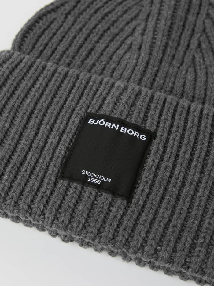 Close-up of the Centre Knit Beanie in Asphalt (Grey) featuring a ribbed texture and black label with a white logo. - Image 2