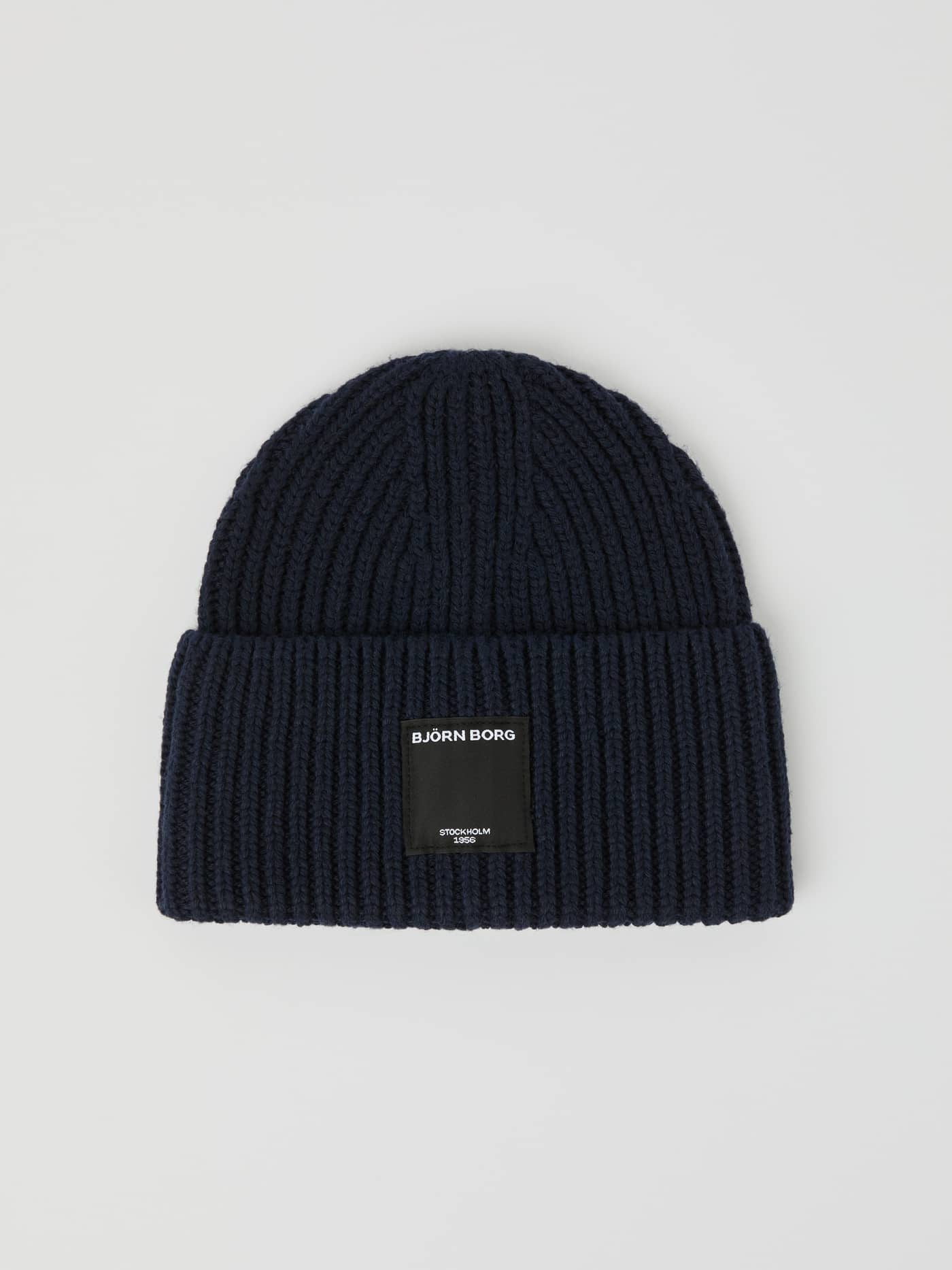 Centre Knit Beanie i Night sky (Marinblå) sedd framifrån med ribbstickad struktur, uppvikt kant och svart logotypetikett. - Image 1