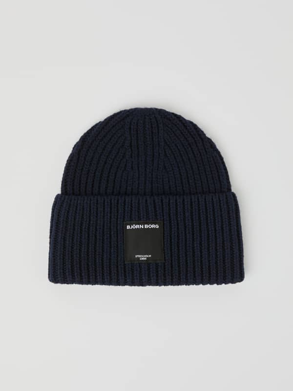 Vue de face du Centre Knit Beanie côtelé en Night sky (Bleu marine) avec bord replié et étiquette logo à l'avant.
