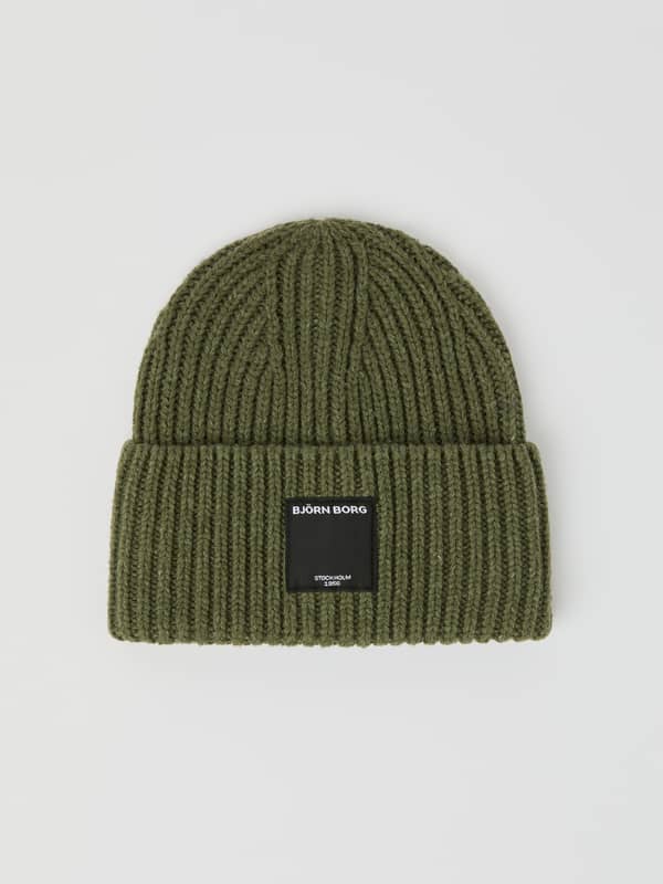 Vue de face du Centre Knit Beanie en Dusty Olive (Vert) avec maille côtelée douce, bord replié et étiquette logo noire.