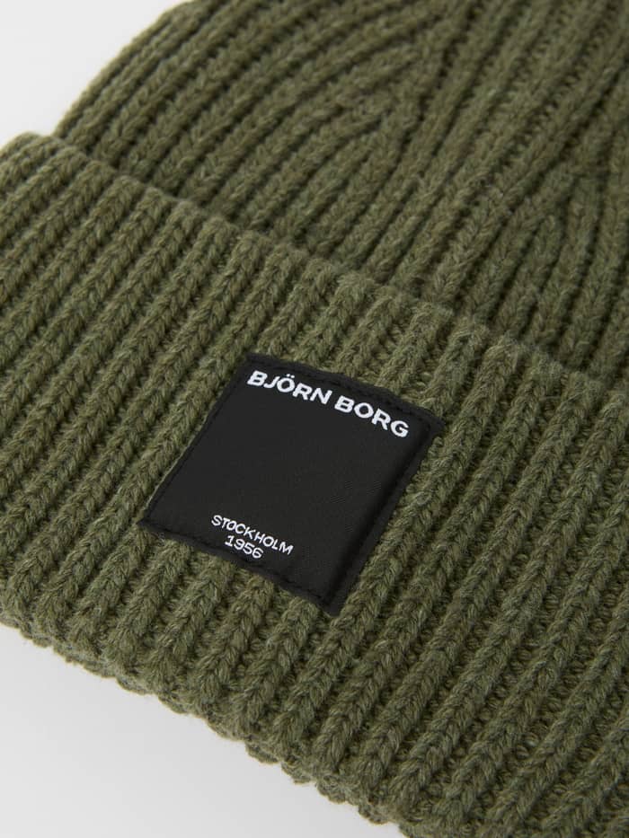 Close-up of the oversized Centre Knit Beanie in Dusty Olive (Green) highlighting the ribbed texture and front label. - Image 2