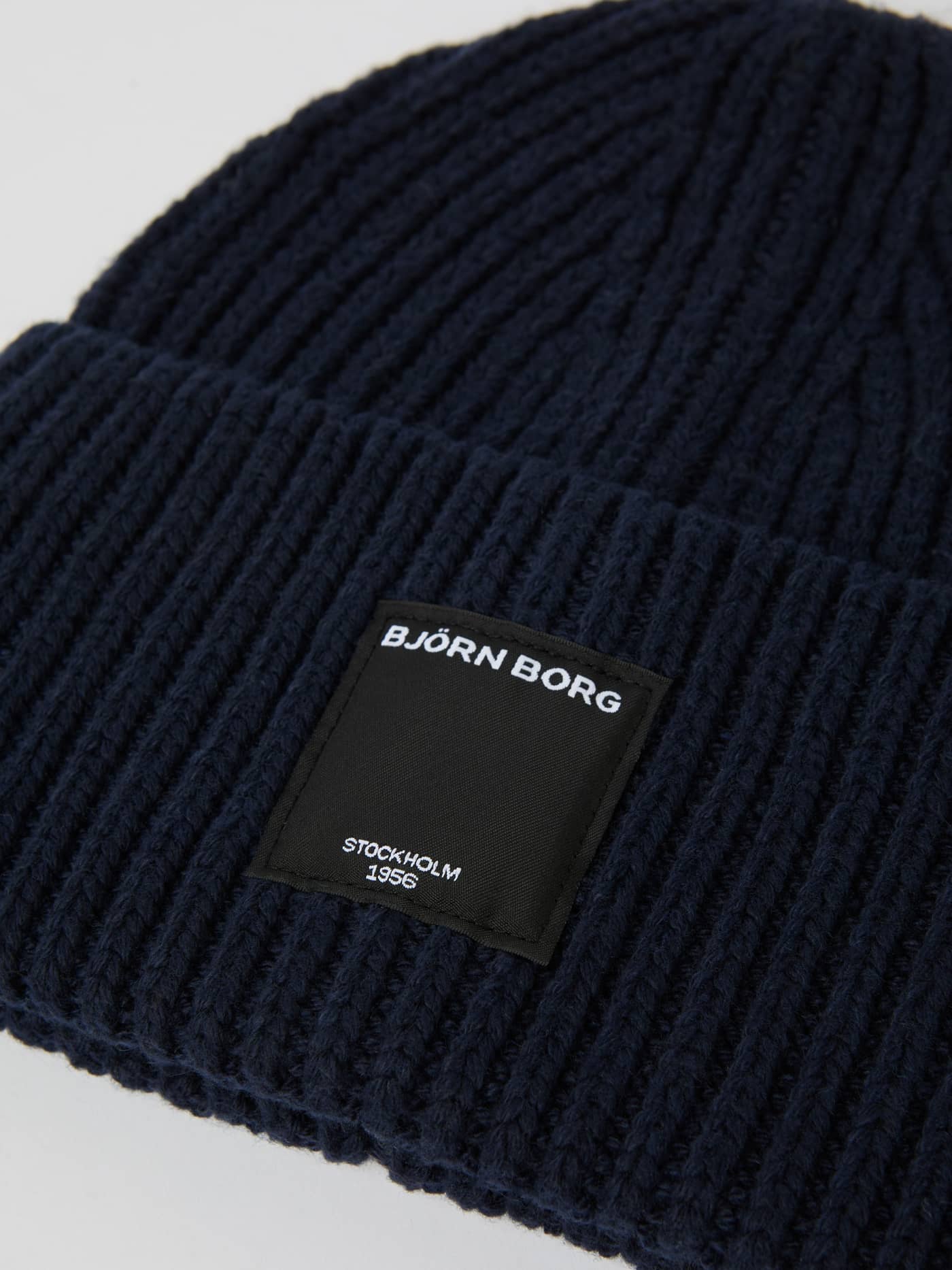 Centre Knit Beanie in Night sky (Marineblau) aus weichem Rippstrick mit schwarzem Logo-Label in der Nahaufnahme. - Image 2