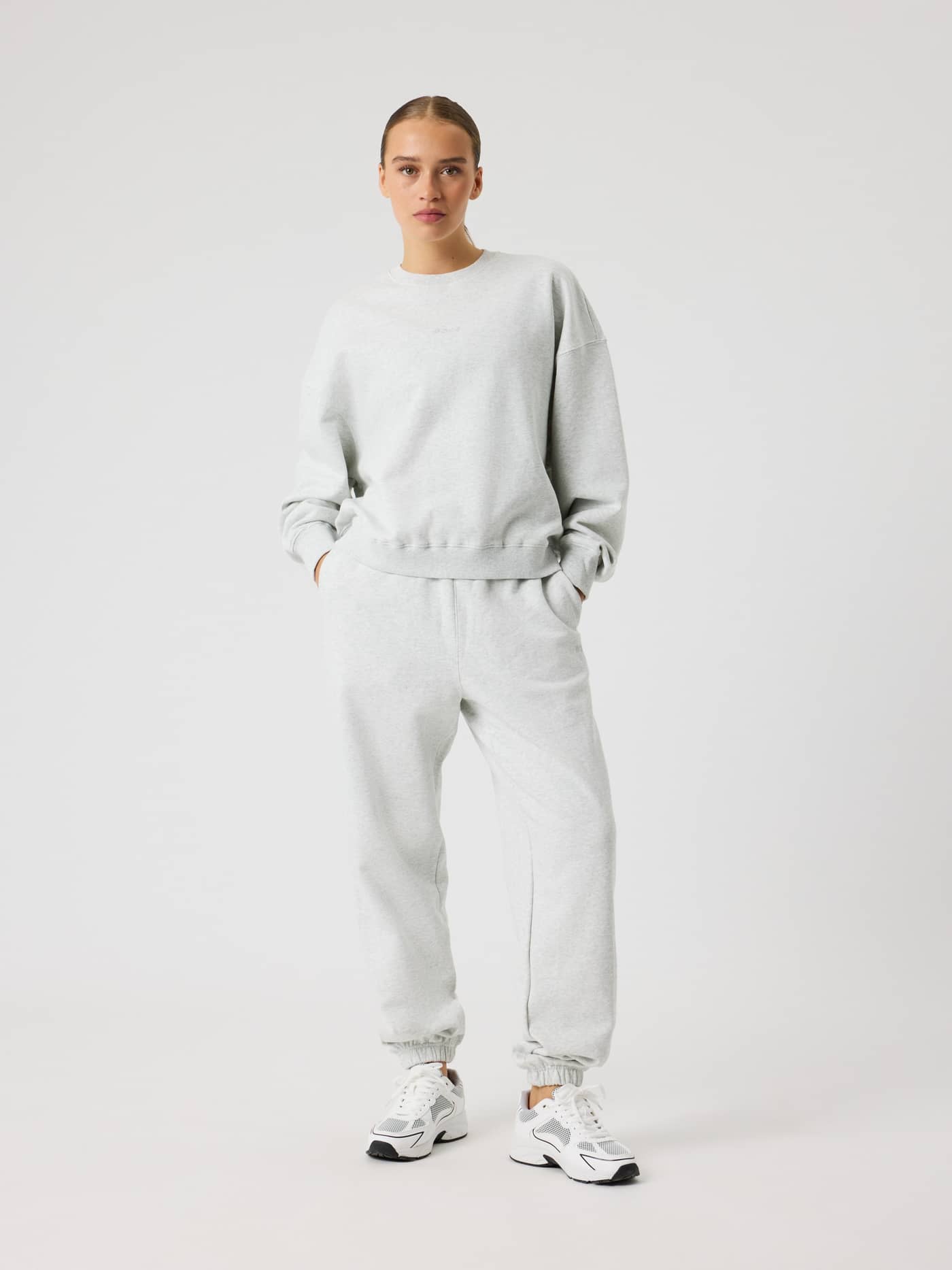 Full-body front view of a woman in the Studio Oversized Sweatpants in Ultra Light Grey Melange (Grey) for studio or leisure. - Image 3