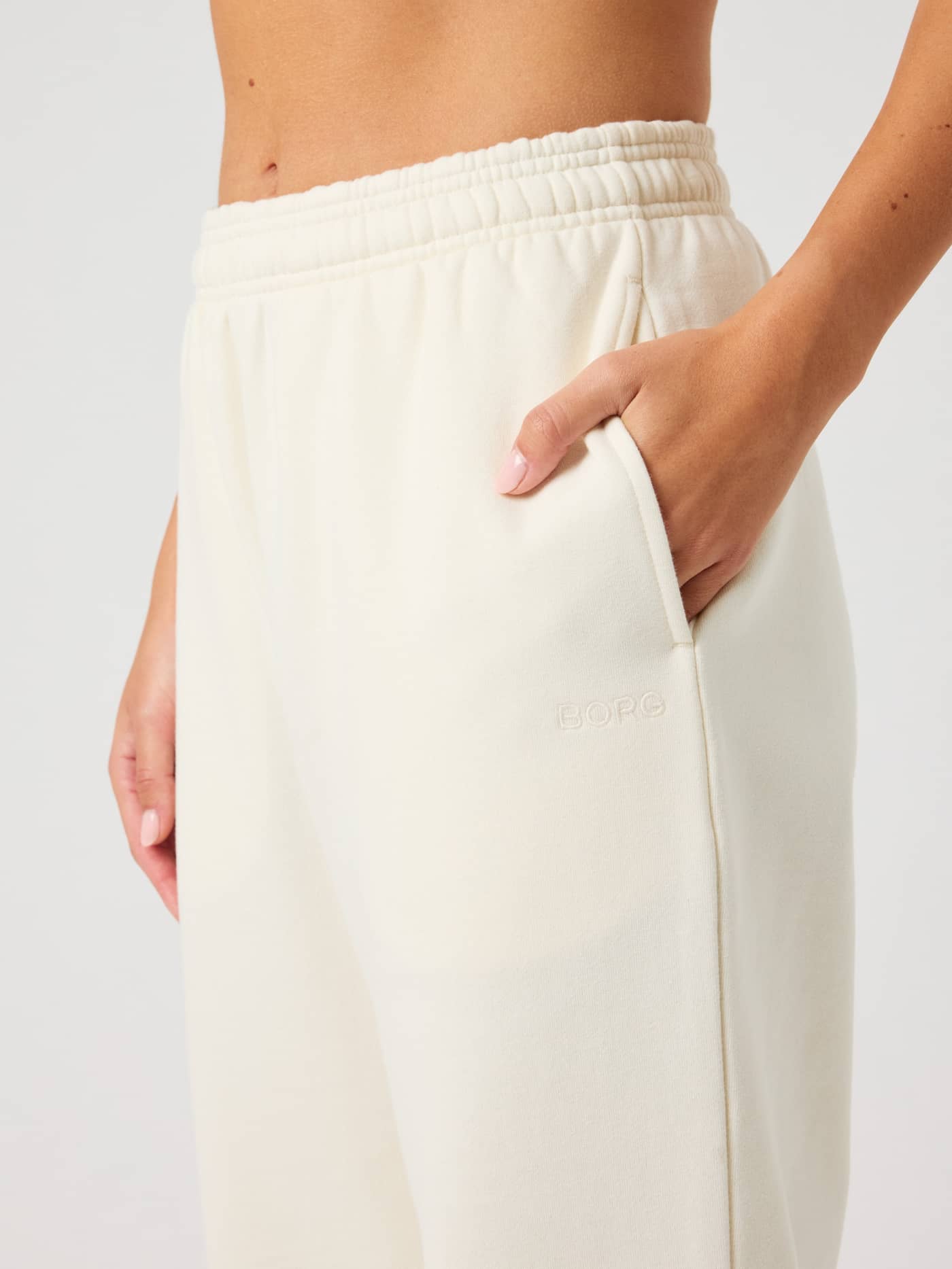 Close-up of the Studio Oversized Sweatpants in Tofu (White), featuring a high-waisted fit and a tone-on-tone logo. - Image 4