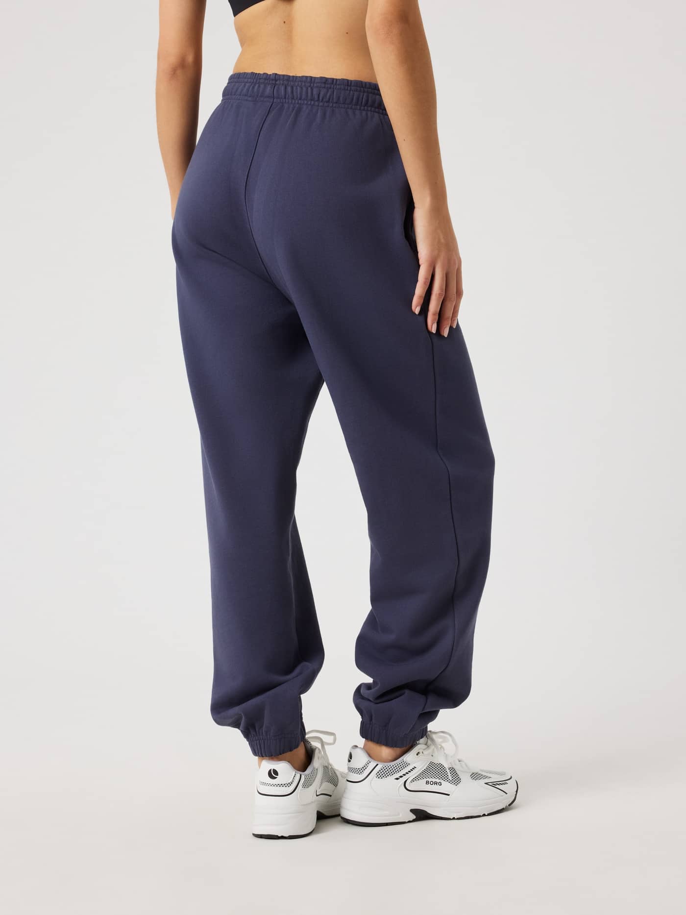 Back view of a woman wearing Studio Oversized Sweatpants in Odyssey Gray (Navy), featuring a high-waisted and relaxed fit. - Image 2