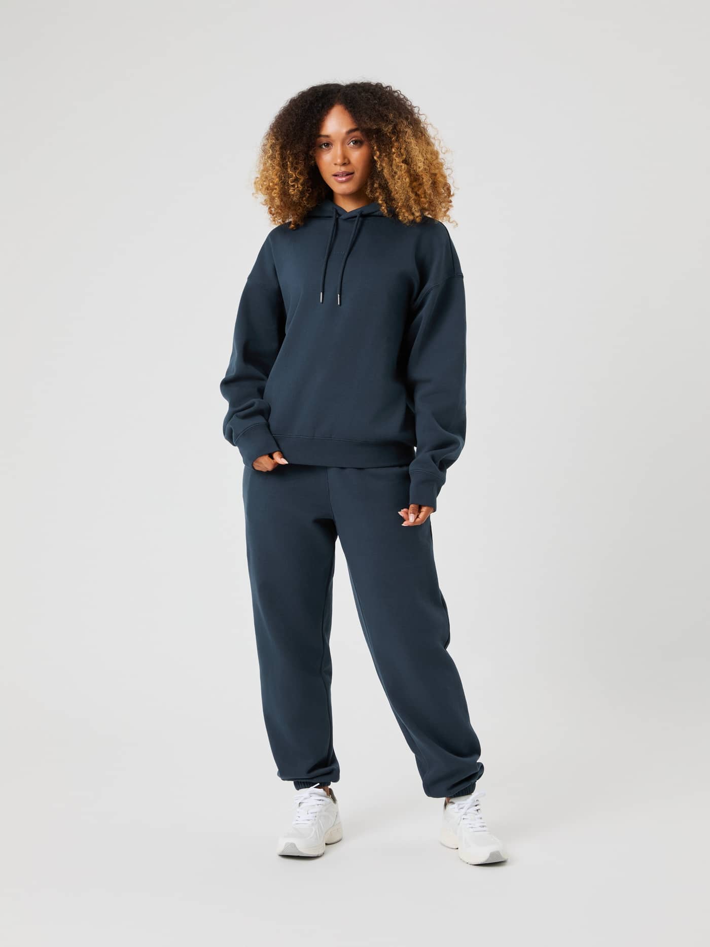 Full-length front view of a woman wearing the Björn Borg Studio Oversized Hoodie in navy blue with matching sweatpants. - Image 3