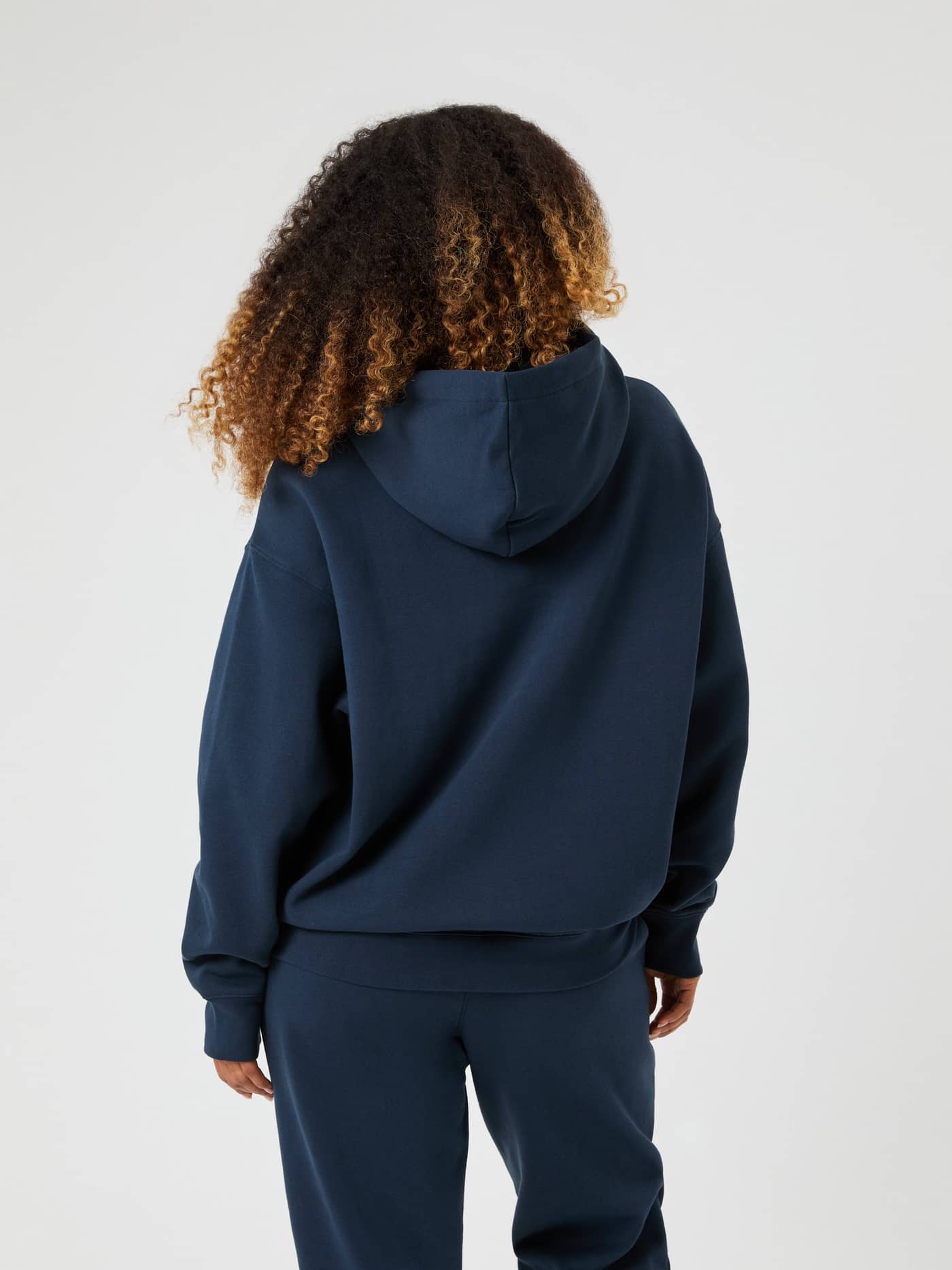 Back view of a woman wearing the Studio Oversized Hoodie in navy blue. - Image 2