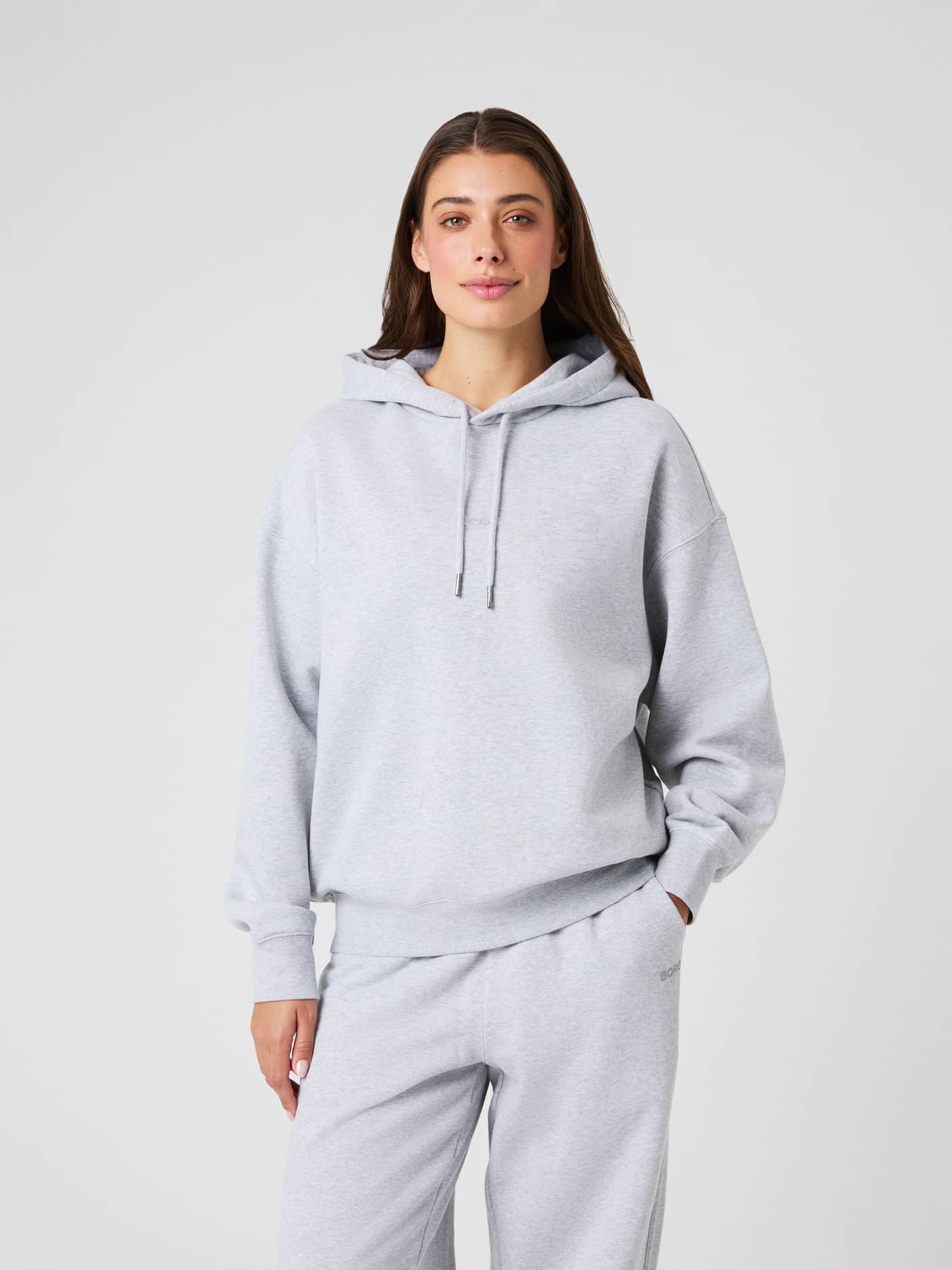 Front view of a woman wearing the Björn Borg Studio Oversized Hoodie in Light Grey Melange (Grey) with a relaxed fit. - Image 2