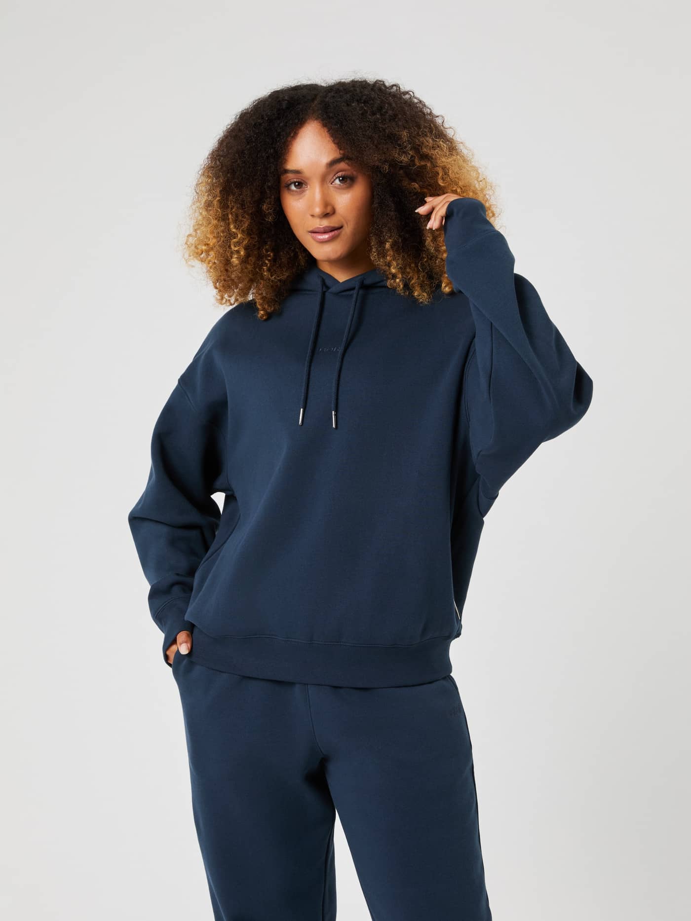 Front view of a woman wearing the Björn Borg Studio Oversized Hoodie in navy blue, paired with matching sweatpants. - Image 1