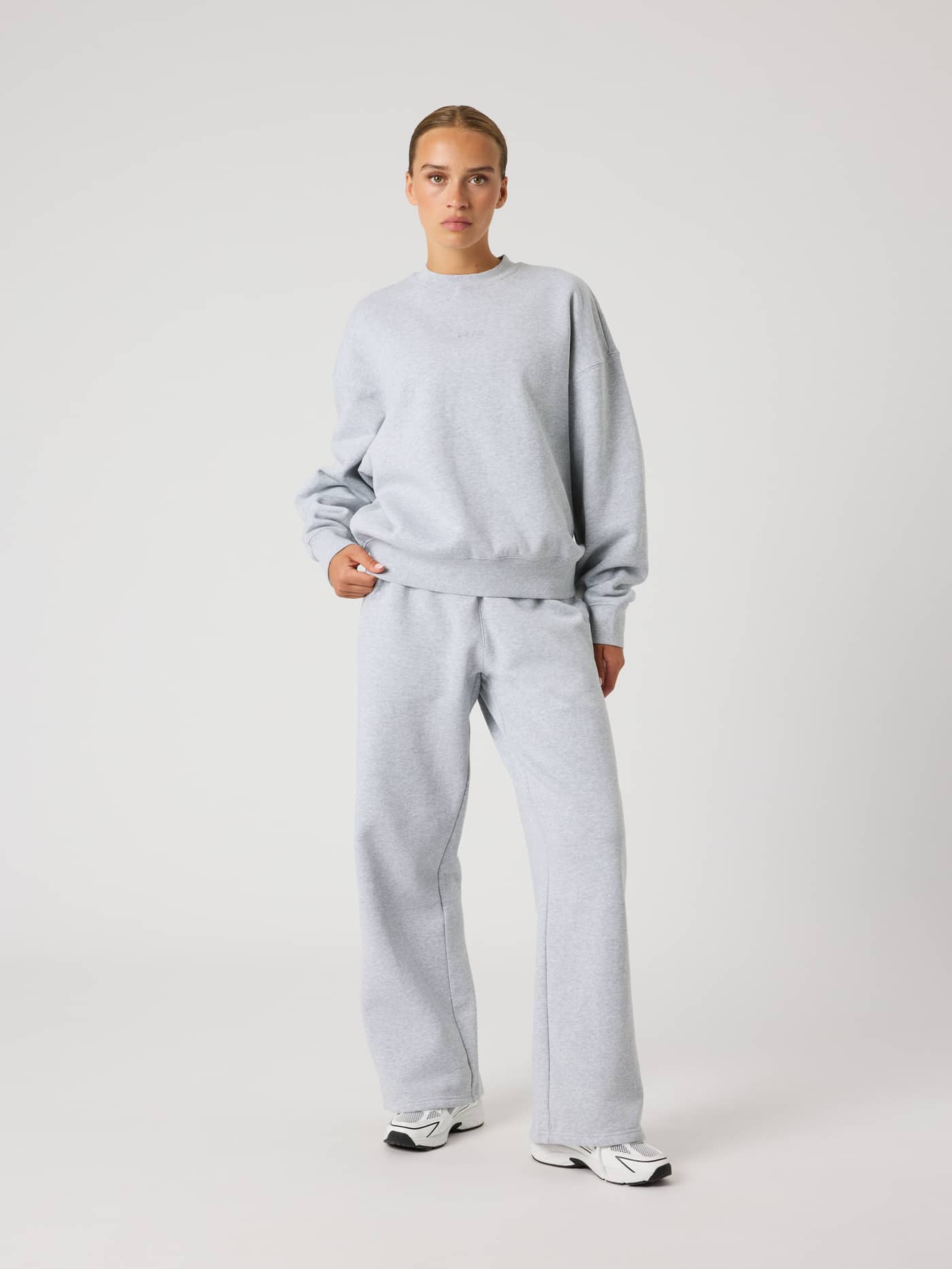 Full-body front view of a woman wearing the Studio Oversized Sweatshirt in Light Grey Melange (Grey) and matching pants. - Image 6