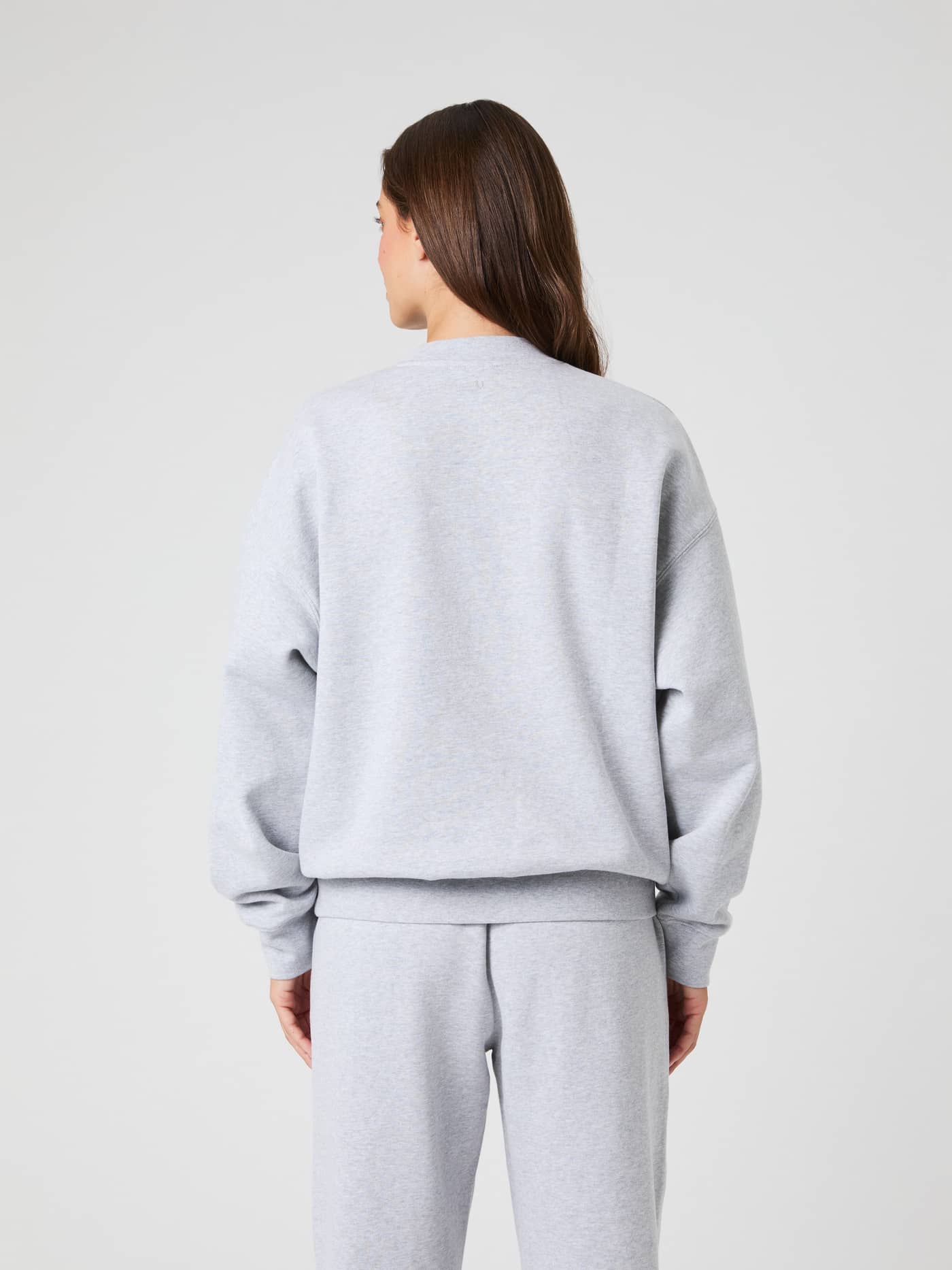 Back view of a model wearing the Studio Oversized Sweatshirt in light grey melange. - Image 3