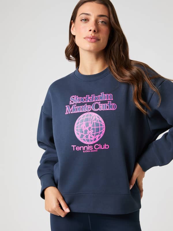 Front view of a woman wearing the oversized Borg Boyfriend Sweatshirt in Outerspace (Navy) with a pink tennis club graphic.