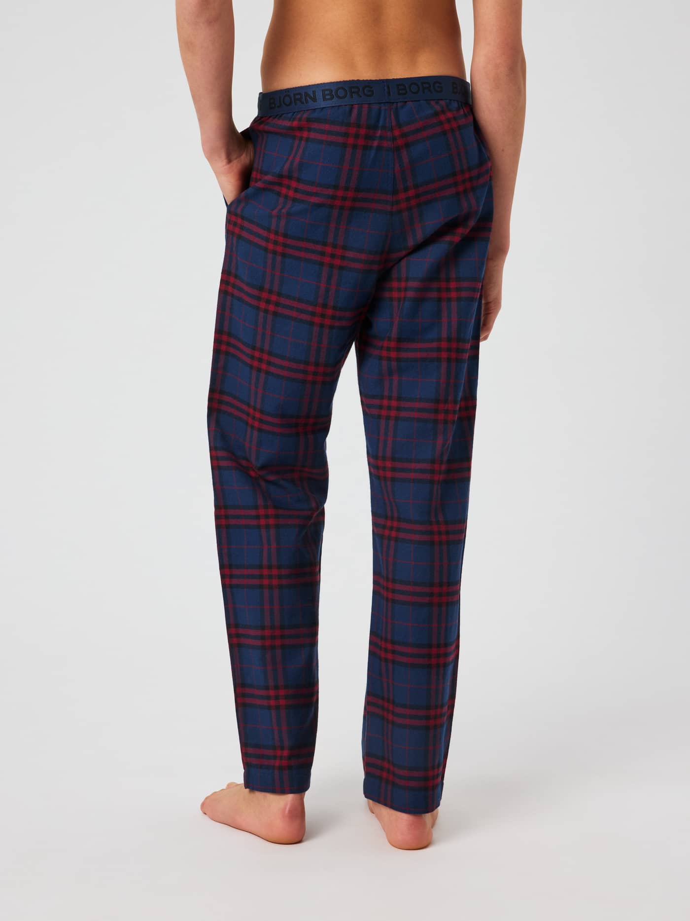 Back view of the Core Pyjama Pants in a red and blue tartan plaid pattern, featuring an elastic waistband with a black logo. - Image 2
